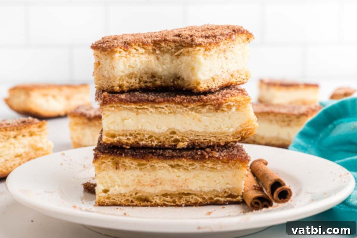 Cinnamon Sugar Cheesecake 2 A stack of perfectly golden brown churro cheesecake bars, dusted with cinnamon sugar, on a white plate, invitingly presented.