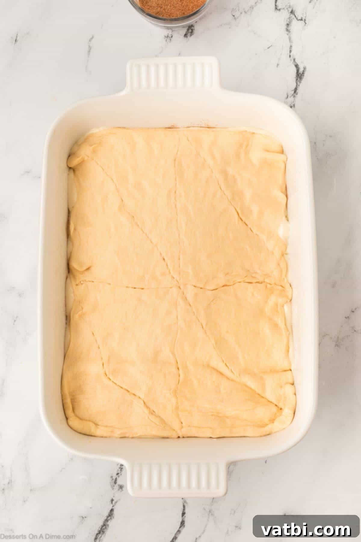 Cinnamon Sugar Cheesecake 11 The second layer of crescent roll dough spread smoothly over the cream cheese filling in the baking dish, sealing the layers.