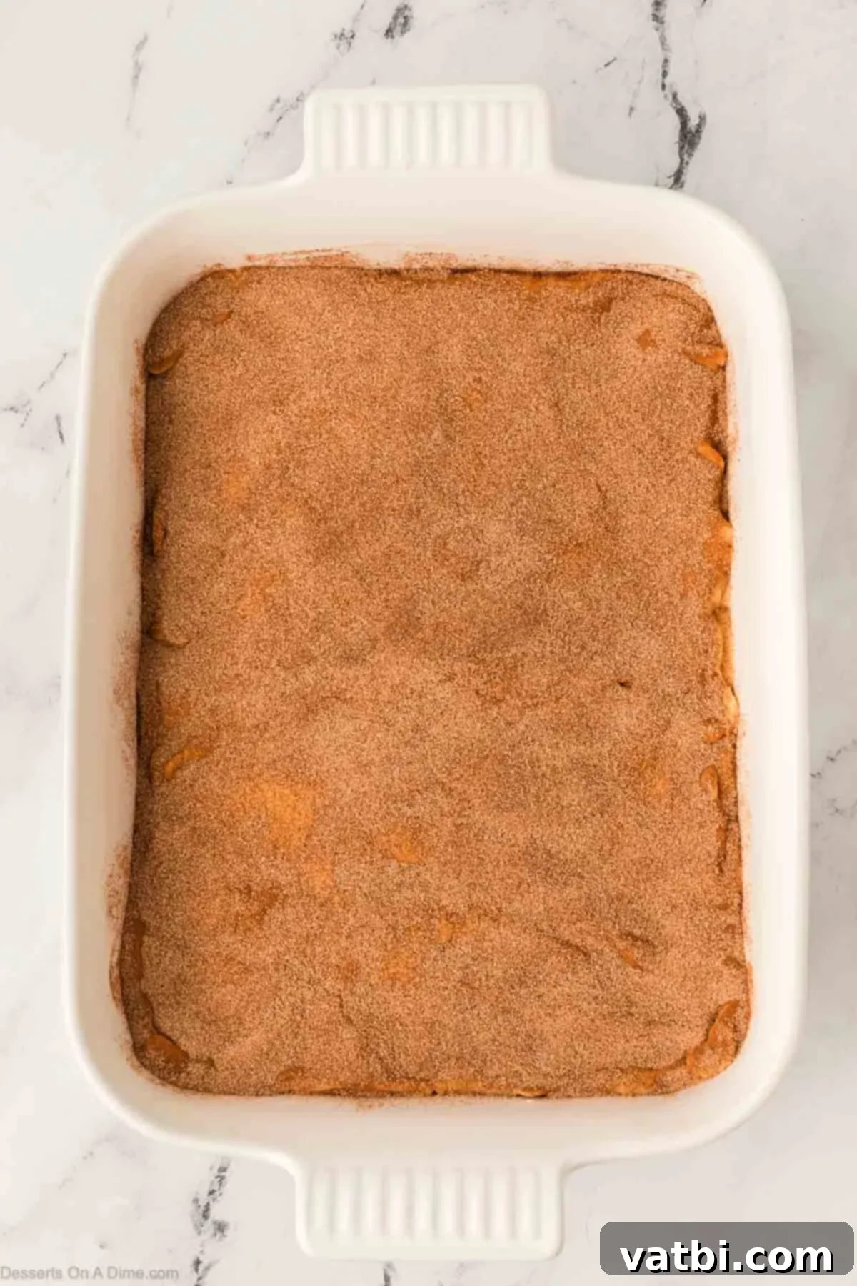 Cinnamon Sugar Cheesecake 12 The remaining cinnamon sugar mixture generously sprinkled over the top crescent roll layer of the churro cheesecake, ready for baking.