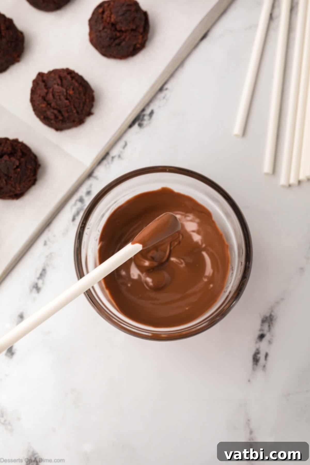 Copycat Starbucks Chocolate Cake Pops 11 The tip of a lollipop stick is dipped into melted chocolate candy melts.