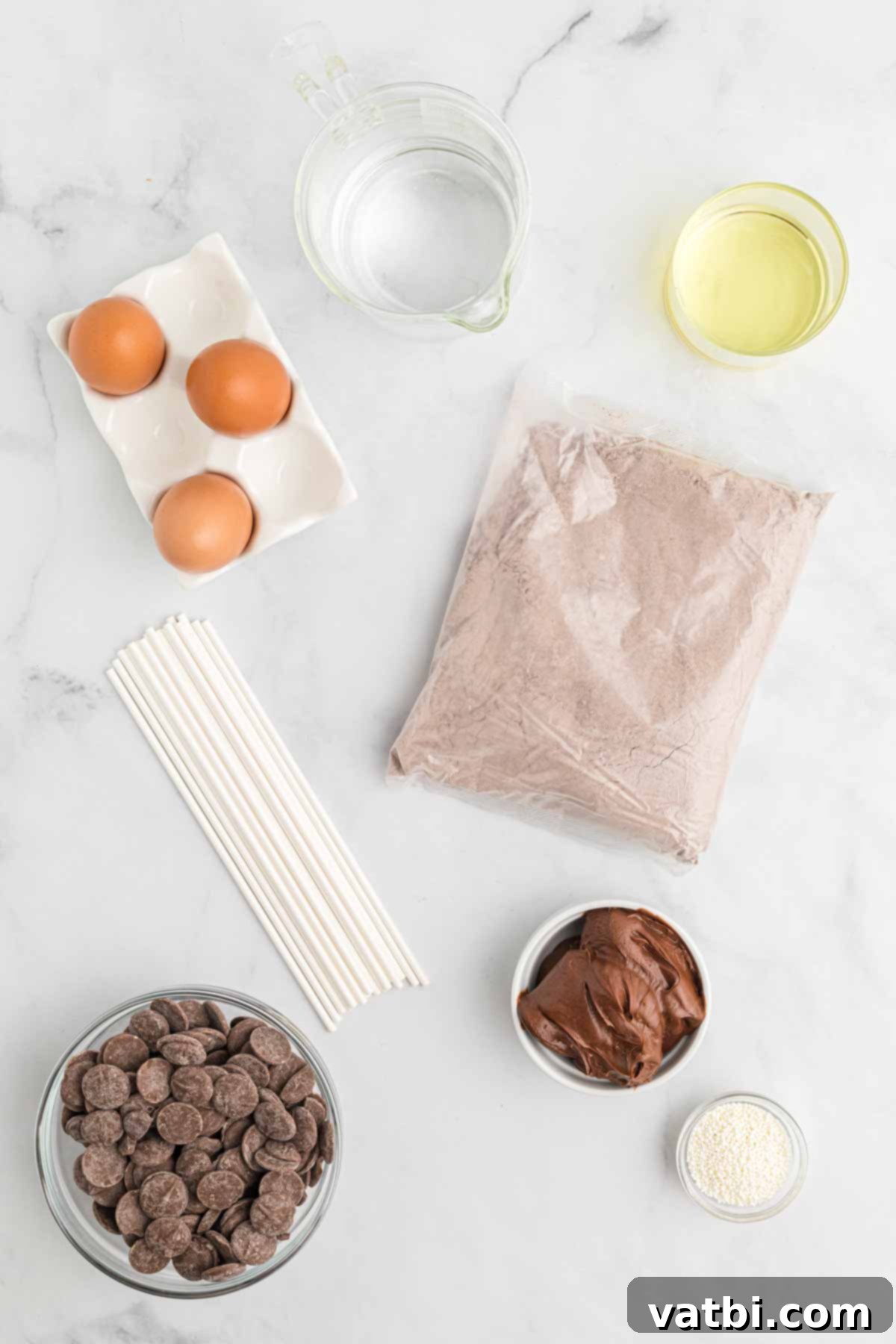 Copycat Starbucks Chocolate Cake Pops 3 A flat lay image showing all the ingredients for Starbucks chocolate cake pops: chocolate cake mix, chocolate fudge frosting, white candy melts, assorted sprinkles, and lollipop sticks.