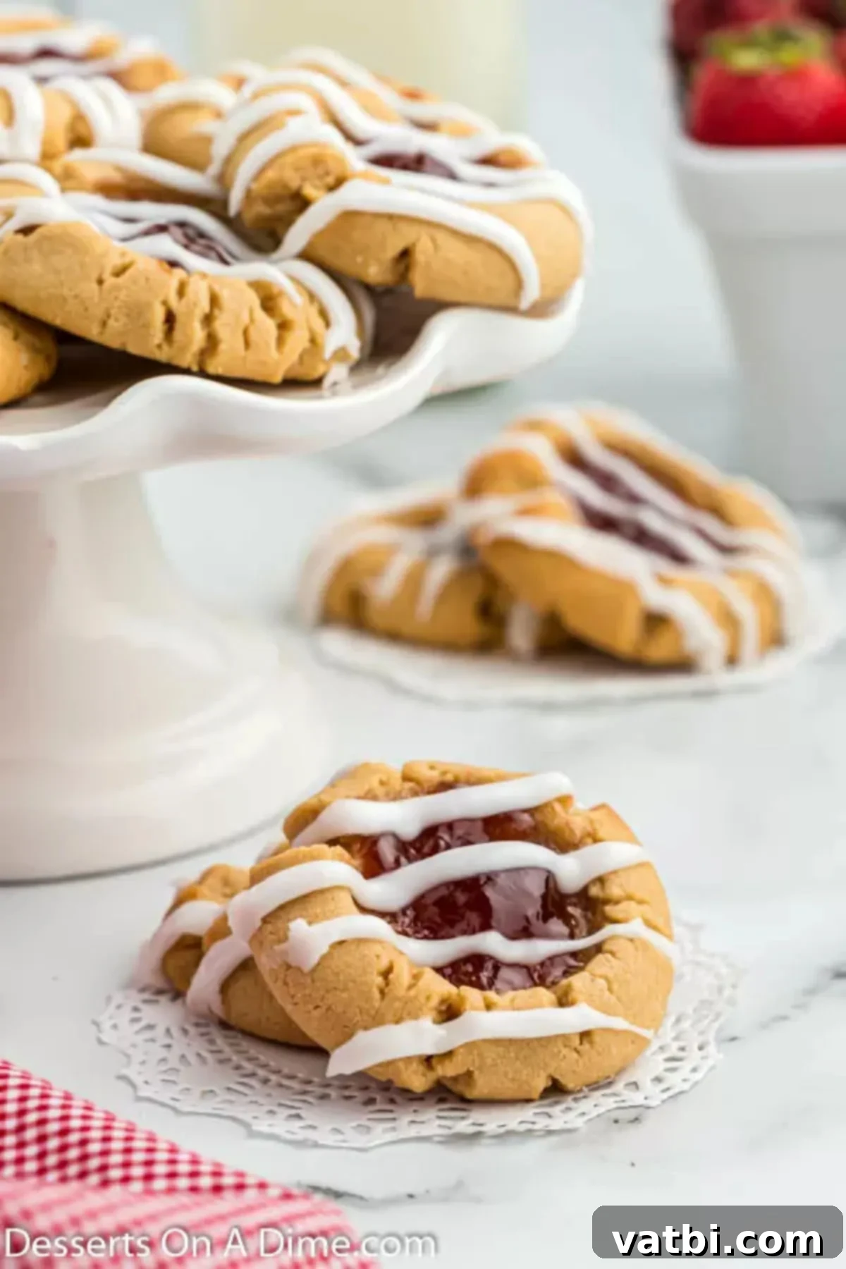 PB&J Cookie Perfection 2 Peanut butter and jelly cookies on a platter. Soft, chewy cookies with a dollop of strawberry jam in the center and a delicate glaze drizzle. Perfect for a nostalgic treat.