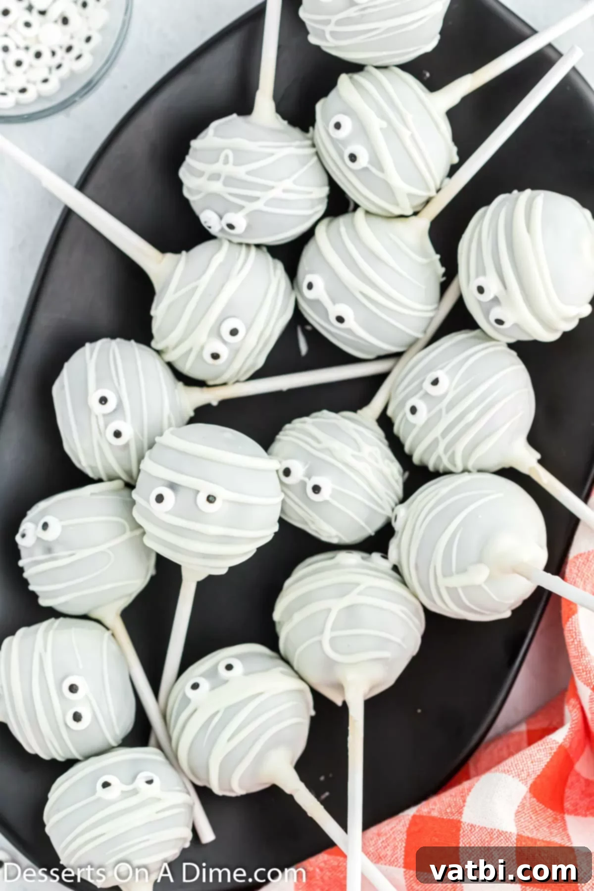 Adorable chocolate mummy cake pops displayed on a white platter, perfect for a Halloween party.