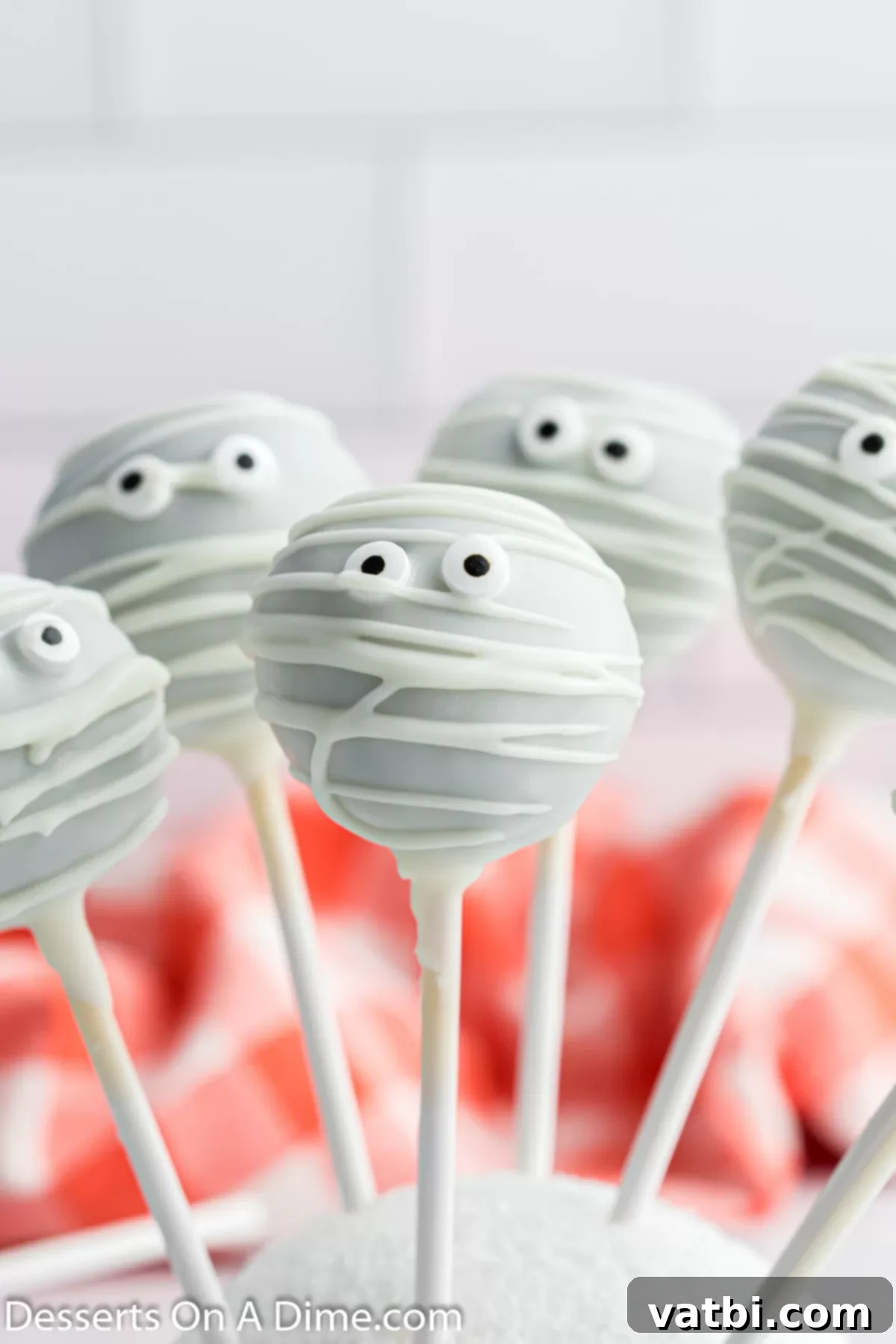 Close-up view of a mummy cake pop with candy eyes and white chocolate drizzle, highlighting the spooky Halloween treat details.