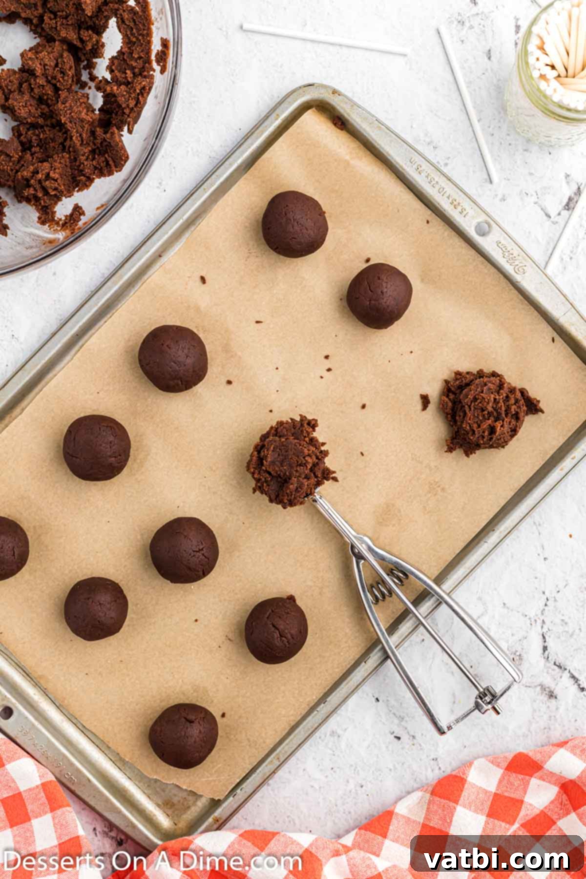 Uniformly shaped chocolate cake balls arranged on a parchment-lined baking sheet, ready for chilling.