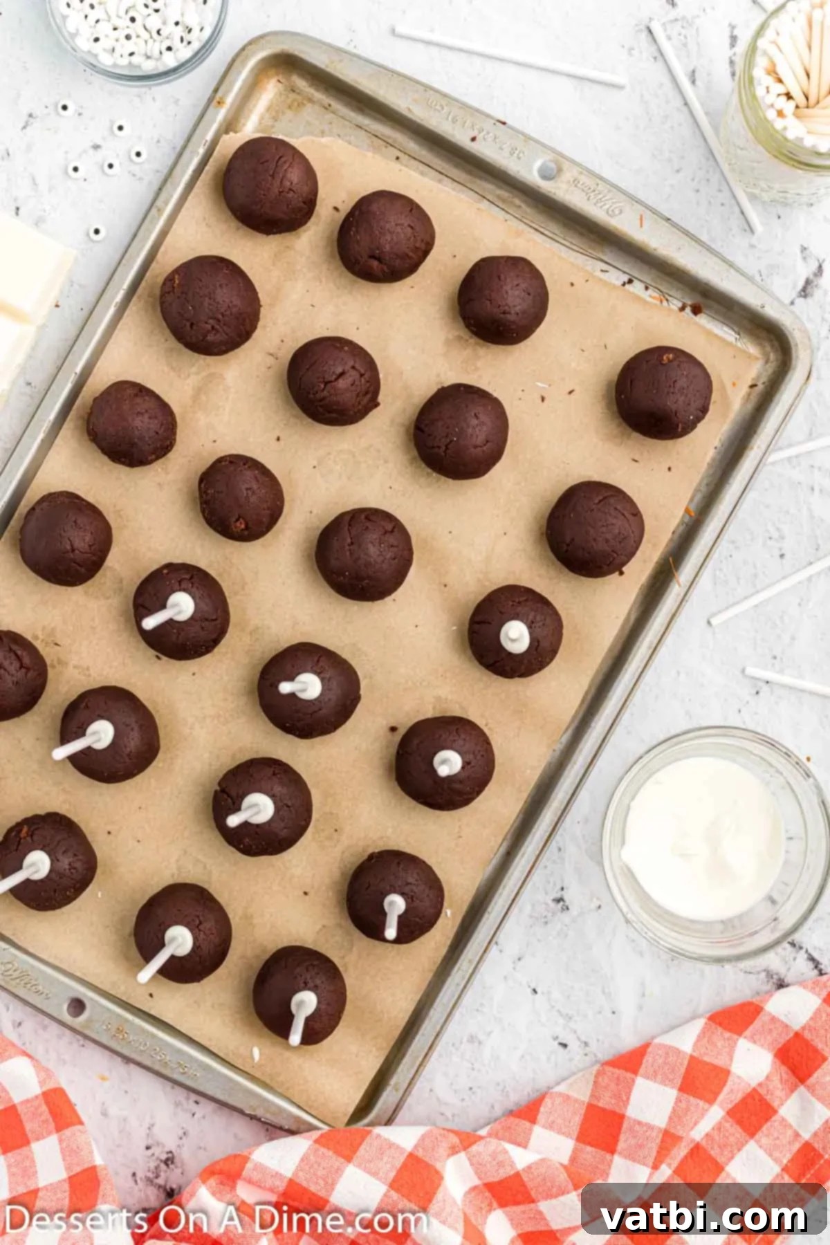 Lollipop sticks inserted halfway into chilled chocolate cake balls, prepped for dipping.