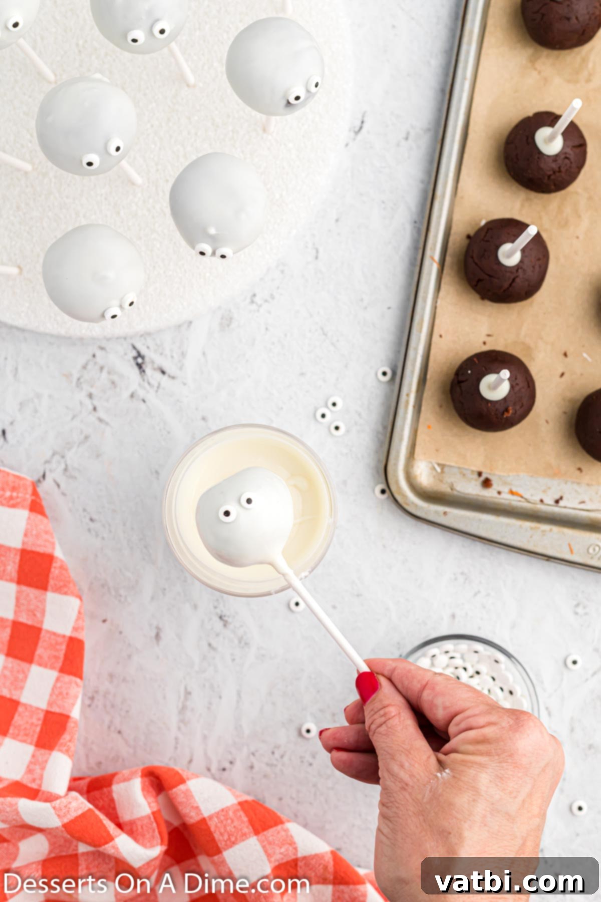 Mummy cake pops with candy eyeballs attached, drying upright on a styrofoam block.