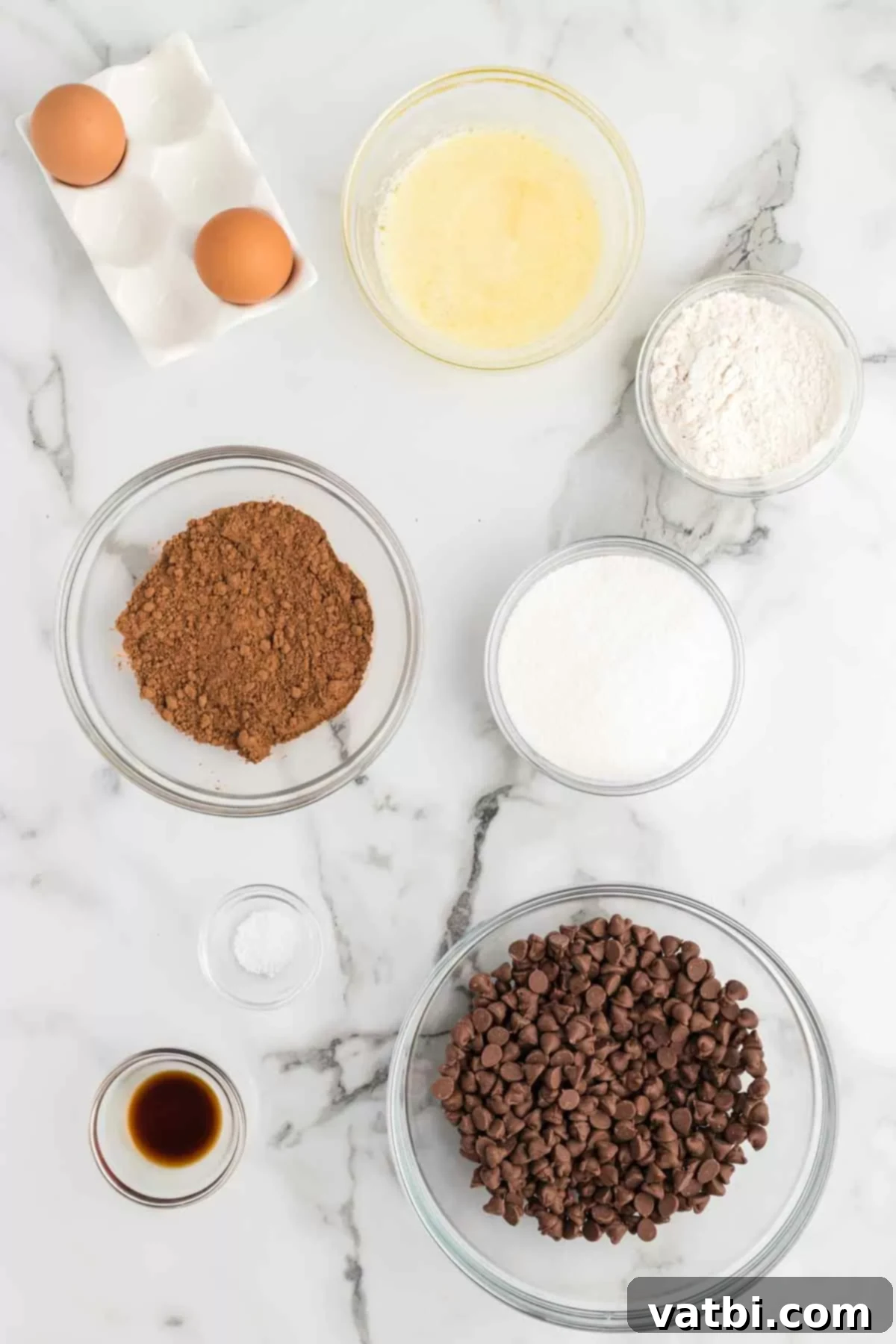 Recreate Starbucks' Famous Brownies at Home 3 Ingredients for Starbucks brownies laid out on a counter: butter, sugar, eggs, vanilla, flour, cocoa, salt, chocolate chips.