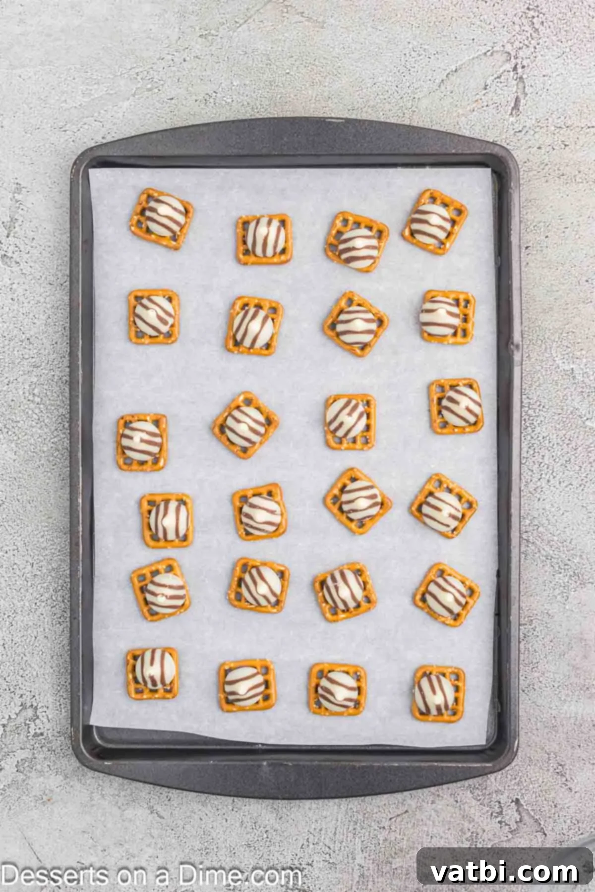 Hershey Hugs candies, unwrapped and carefully placed on top of each square pretzel, ready for melting.