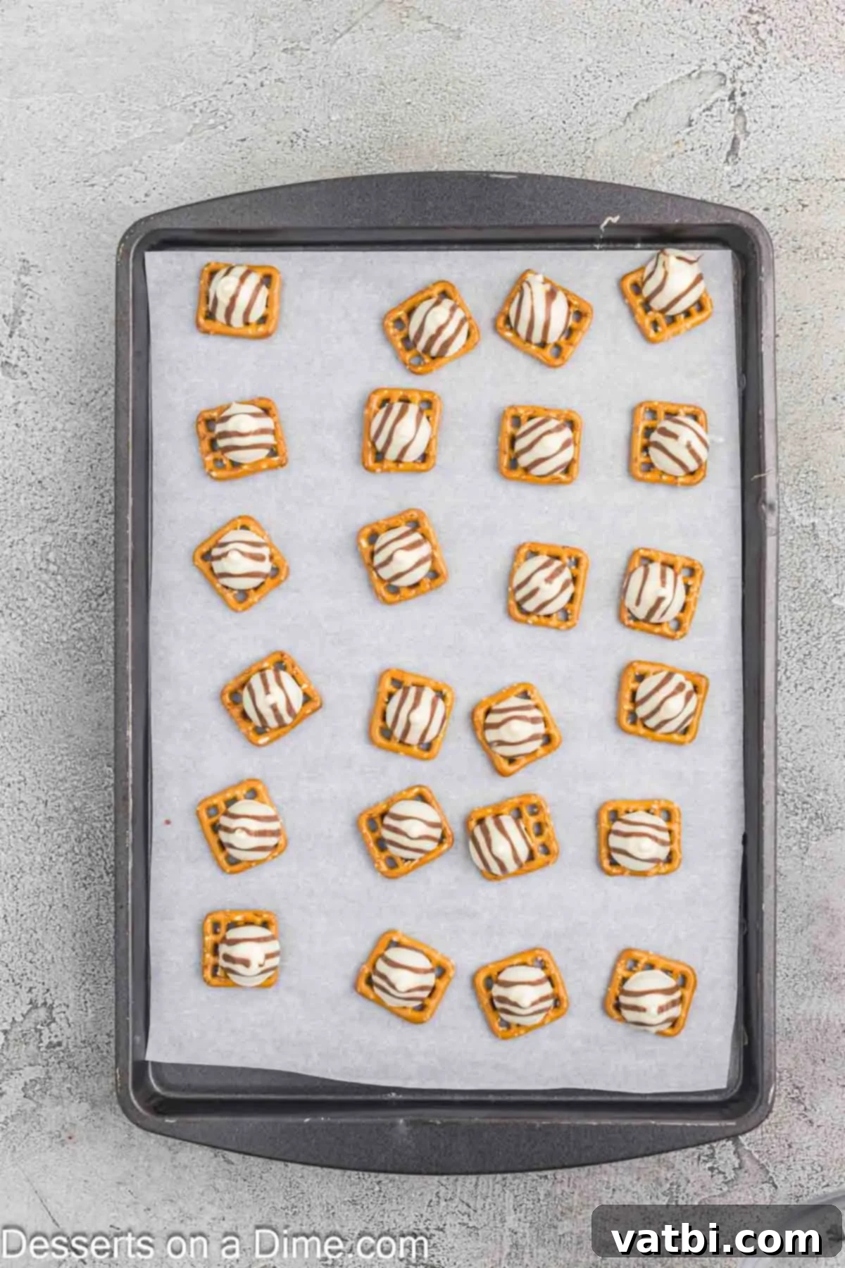 Melted Hershey Hugs gently pressed onto the pretzels after a brief bake, showing they still hold their general shape but are soft.