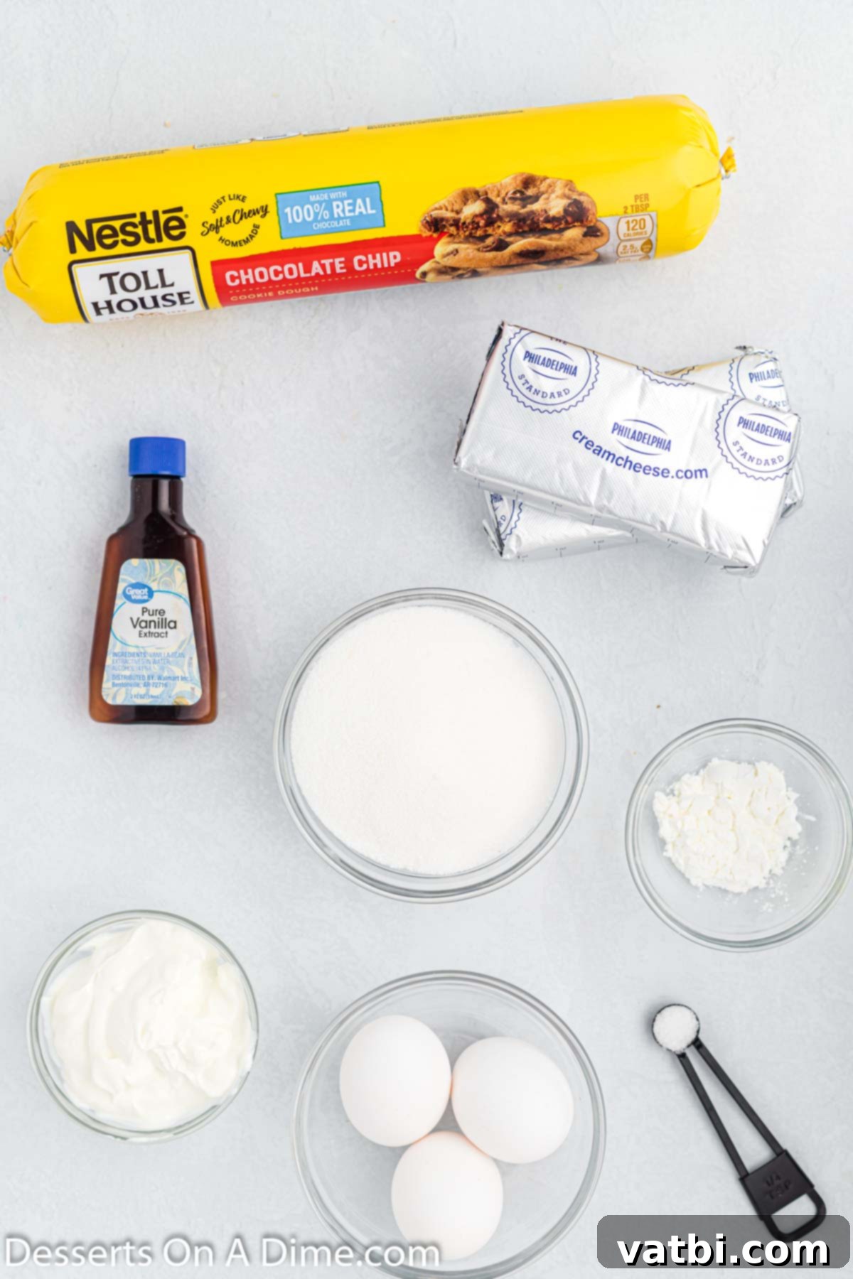 Chocolate Chip Cookie Cheesecake 3 Key ingredients laid out for Chocolate Chip Cookie Cheesecake: cookie dough, cream cheese, vanilla, eggs, powdered sugar.