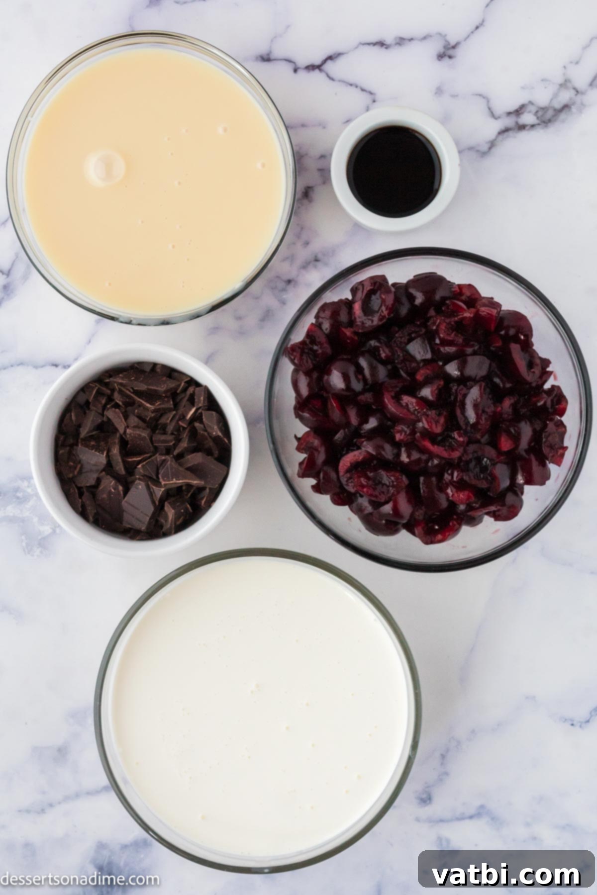 Homemade Cherry Garcia Ice Cream 3 Ingredients for Cherry Garcia ice cream including heavy whipping cream, sweetened condensed milk, vanilla extract, fresh cherries, and dark chocolate chunks on a wooden board.