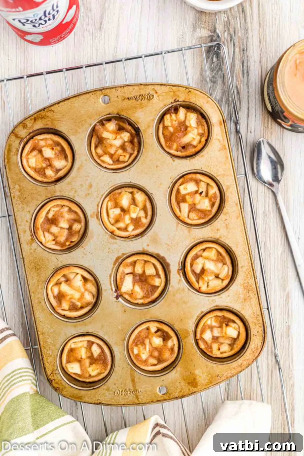 Apple Pie Poppers 11 Baked mini apple pie bites cooling in the muffin pan on a wire rack.