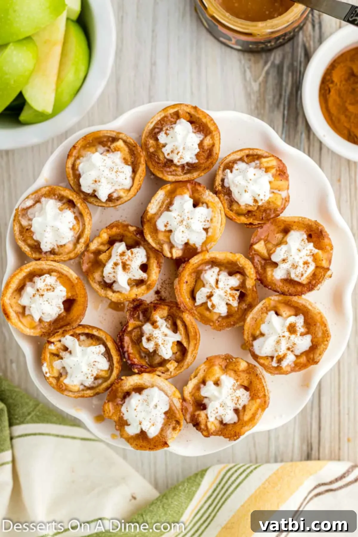 Apple Pie Poppers 12 Finished mini apple pie bites topped with whipped cream and caramel, arranged on a platter.