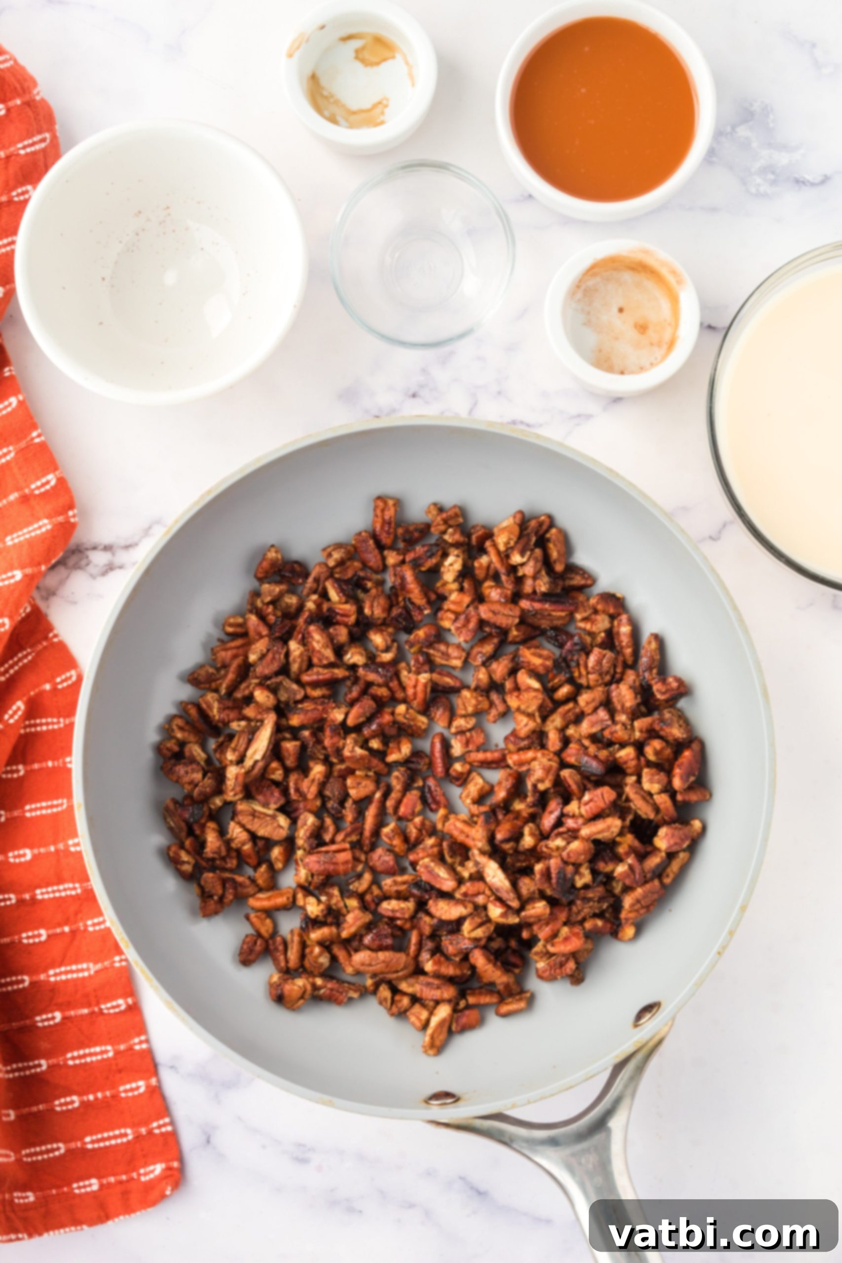 Pecans cooked with melted sugar and seasoning, creating a sticky praline coating.
