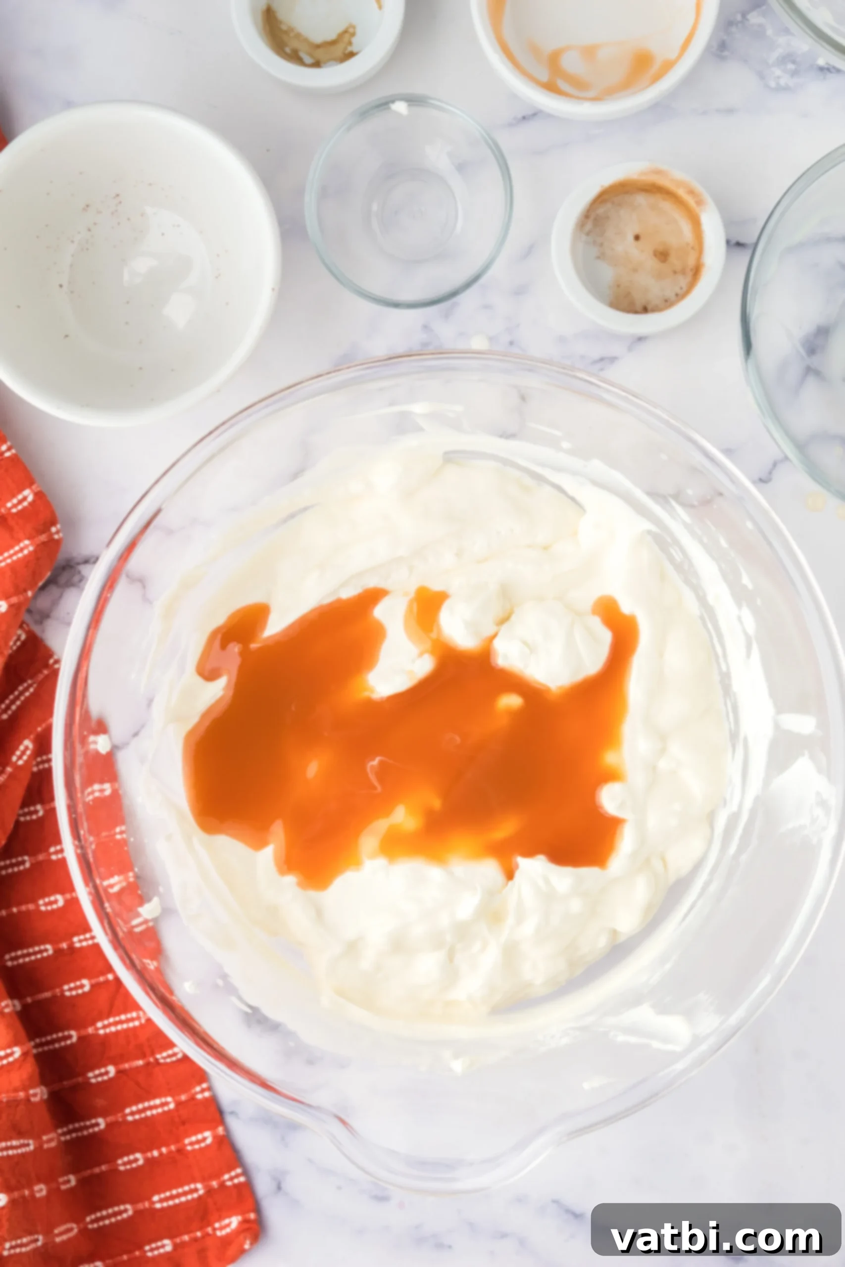 Caramel sauce being added and swirled into the whipped cream and condensed milk mixture.