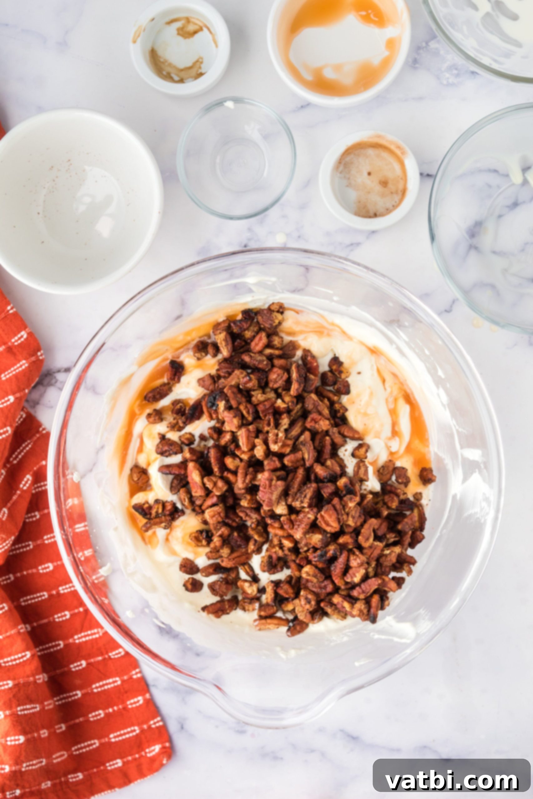 Candied pecans being folded into the creamy ice cream mixture.