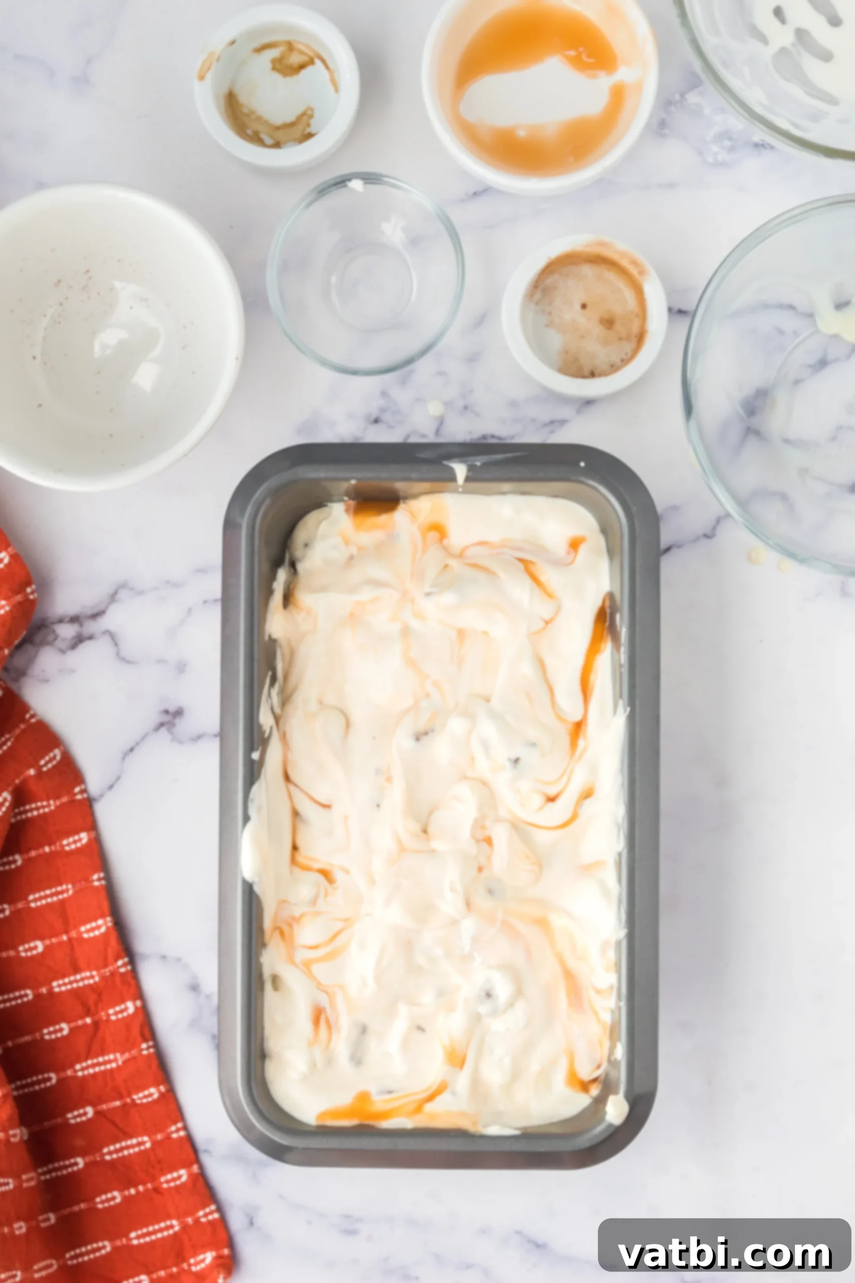 Ice cream mixture spread evenly into a metal loaf pan, ready for freezing.