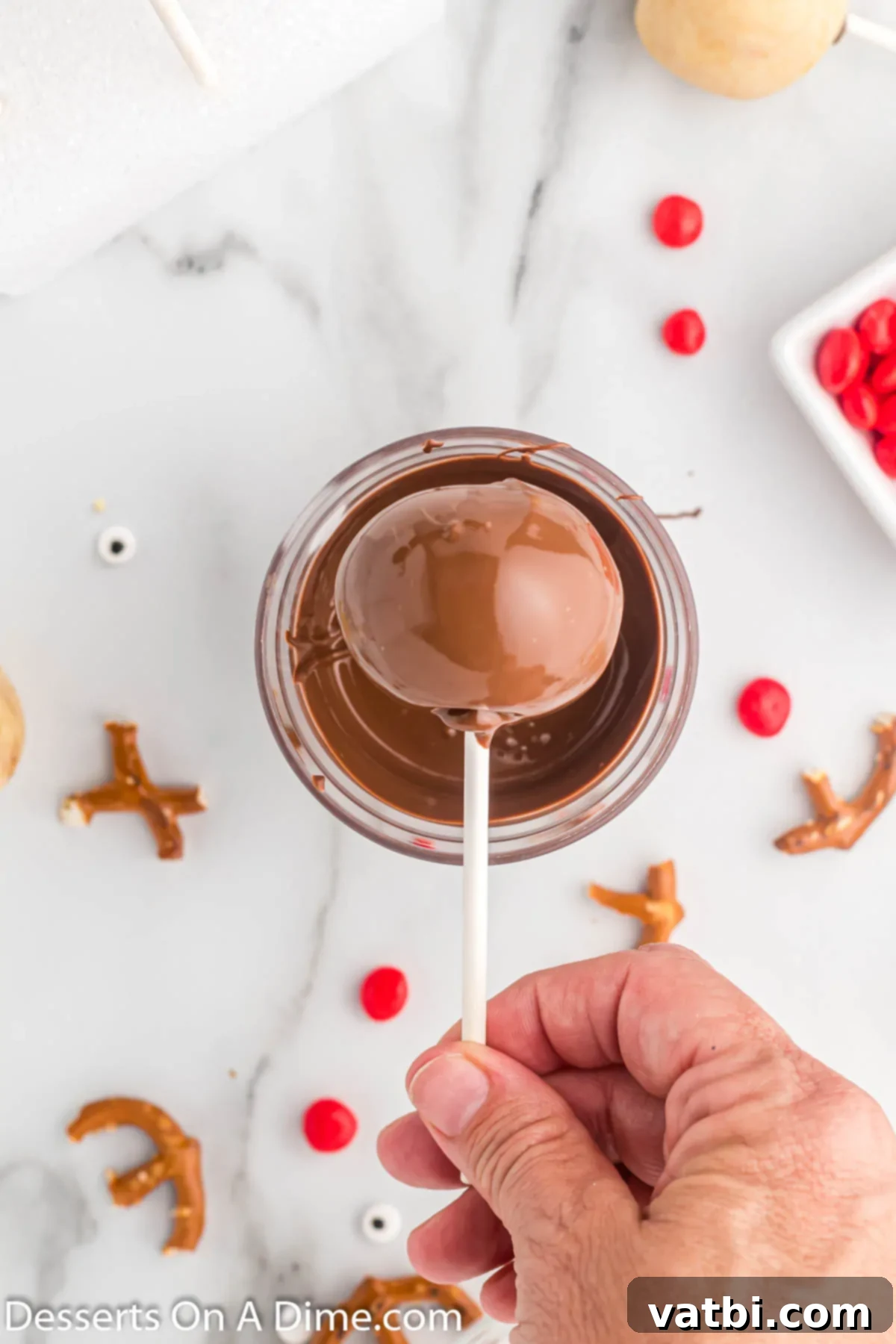 Festive Reindeer Cake Pops 7 Cake pop dipped in chocolate. A cake pop being carefully dipped into melted chocolate coating.