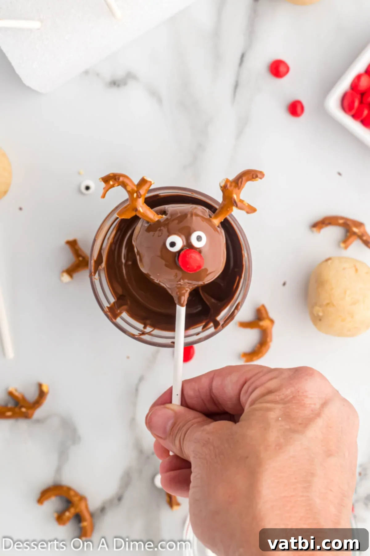 Festive Reindeer Cake Pops 8 Antlers, eyes and nose added to each cake pop. A decorated reindeer cake pop with candy eyes, a red hot nose, and pretzel antlers.