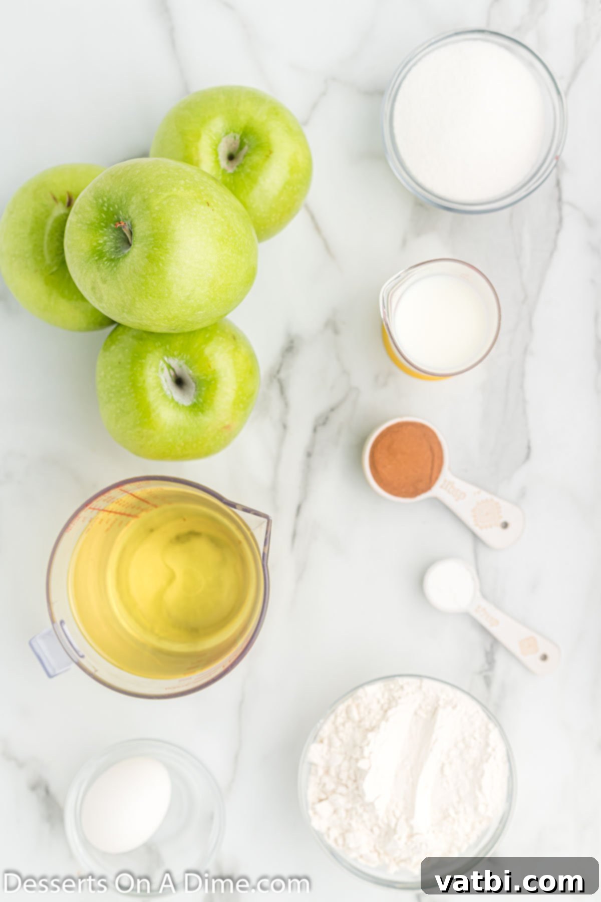 Golden Apple Fritters 3 Ingredients for deep fried apples: apples, oil, flour, baking powder, sugar, milk, egg, cinnamon arranged on a wooden surface.