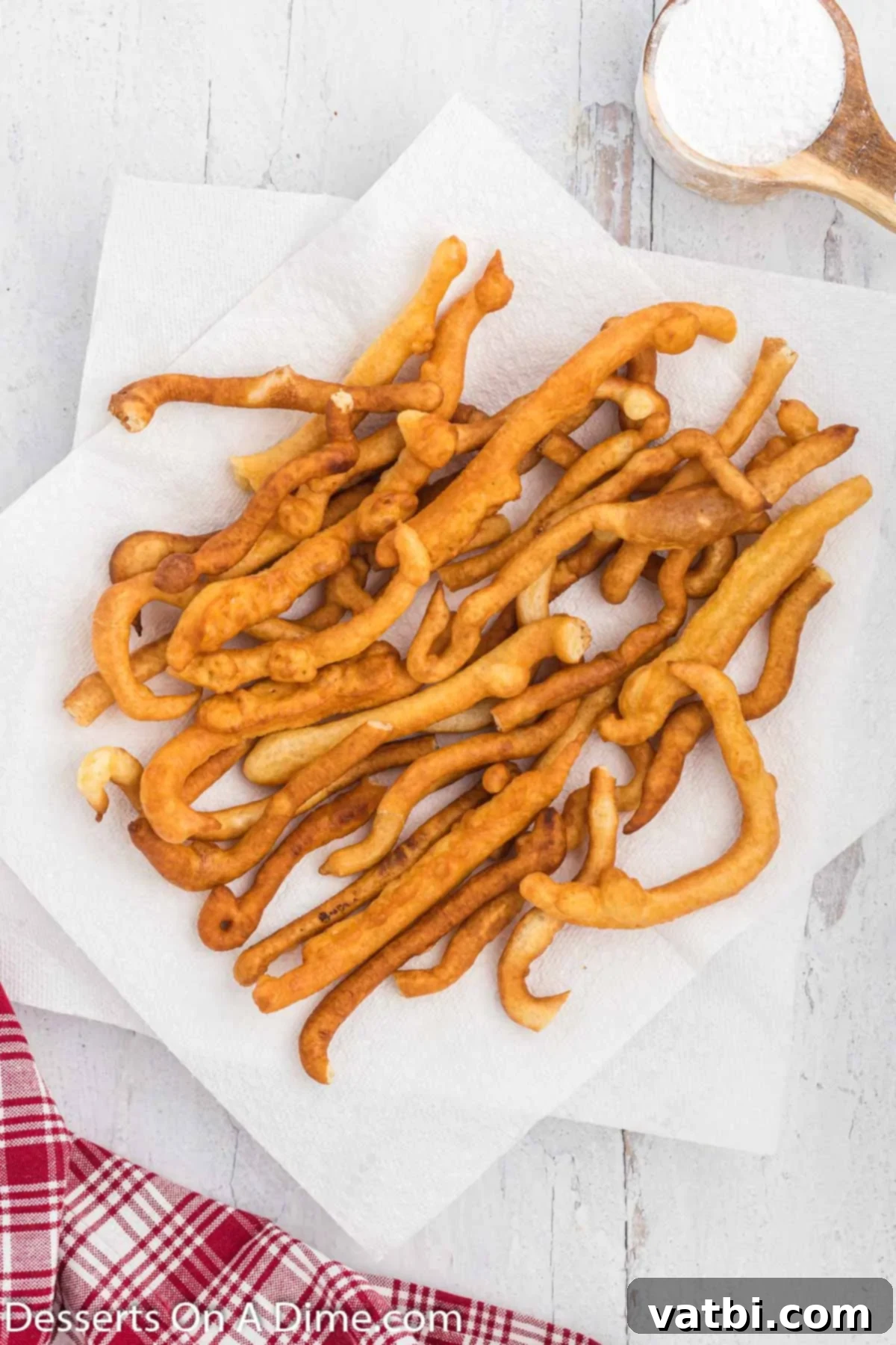 Crispy Funnel Sticks 7 Funnel cake fries on a paper towel lined plate.