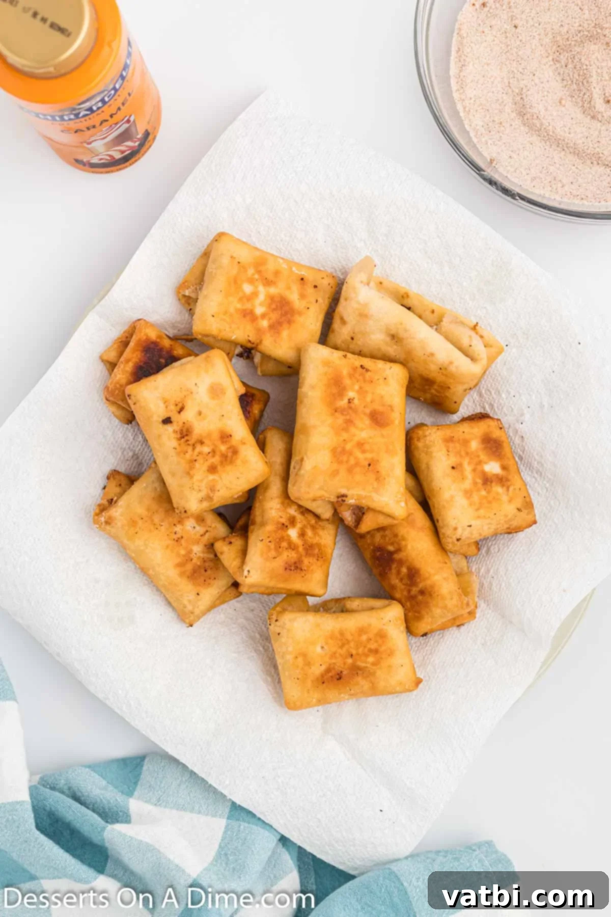 Crispy Cheesecake Dessert Chimis 8 Platter of fried chimichangas on a paper towel lined plate.