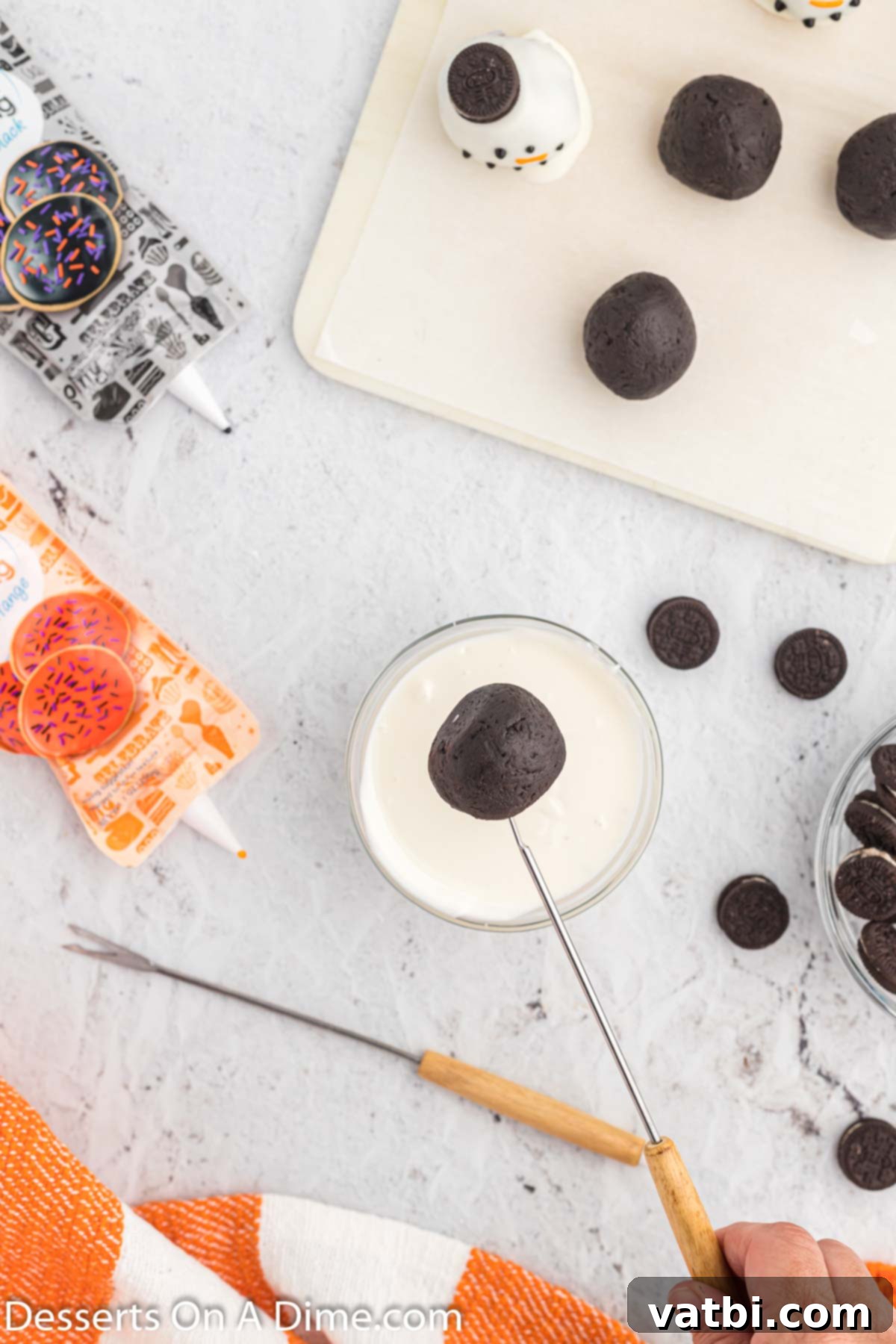 Whimsical Winter Oreo Bites 7 An Oreo ball being held with a fork, ready to be dipped into melted almond bark.