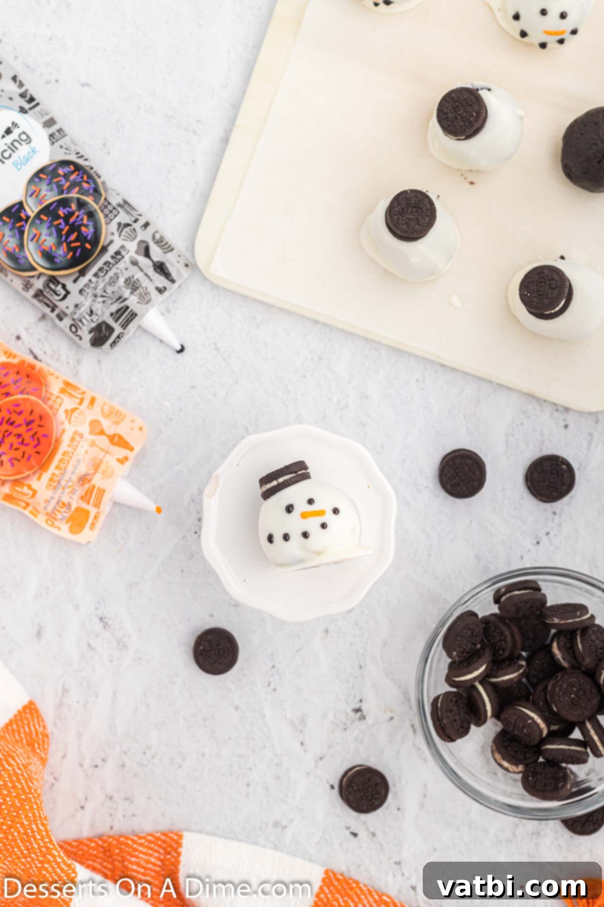Whimsical Winter Oreo Bites 9 An Oreo ball being decorated with icing to form a snowman face.