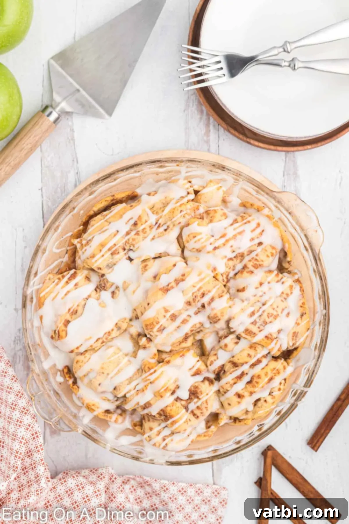 Delicious Cinnamon Roll Apple Pie 8 Baked cinnamon roll apple pie, glistening with icing drizzled on top.