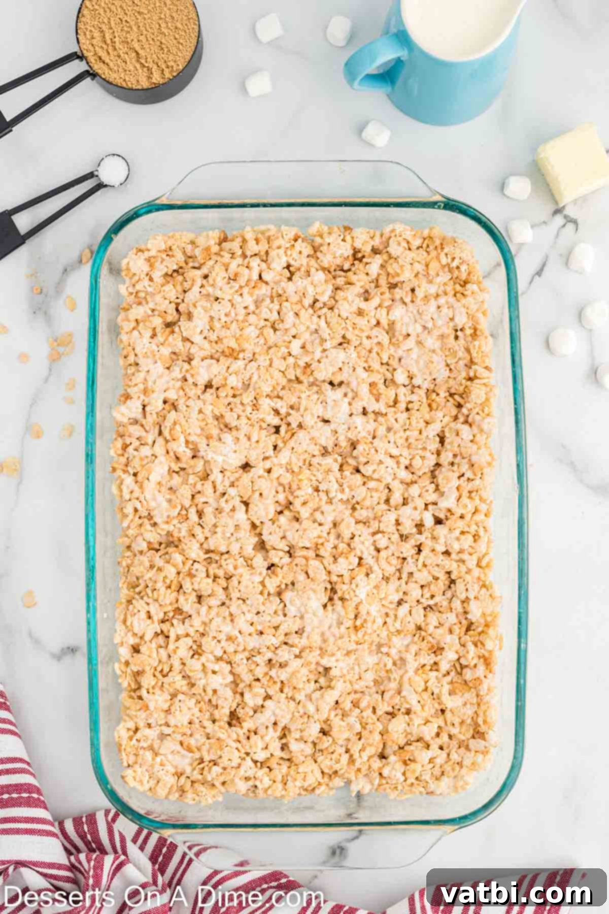 Rice Krispie treat mixture evenly pressed into a 9x13 inch baking pan, ready for chilling.