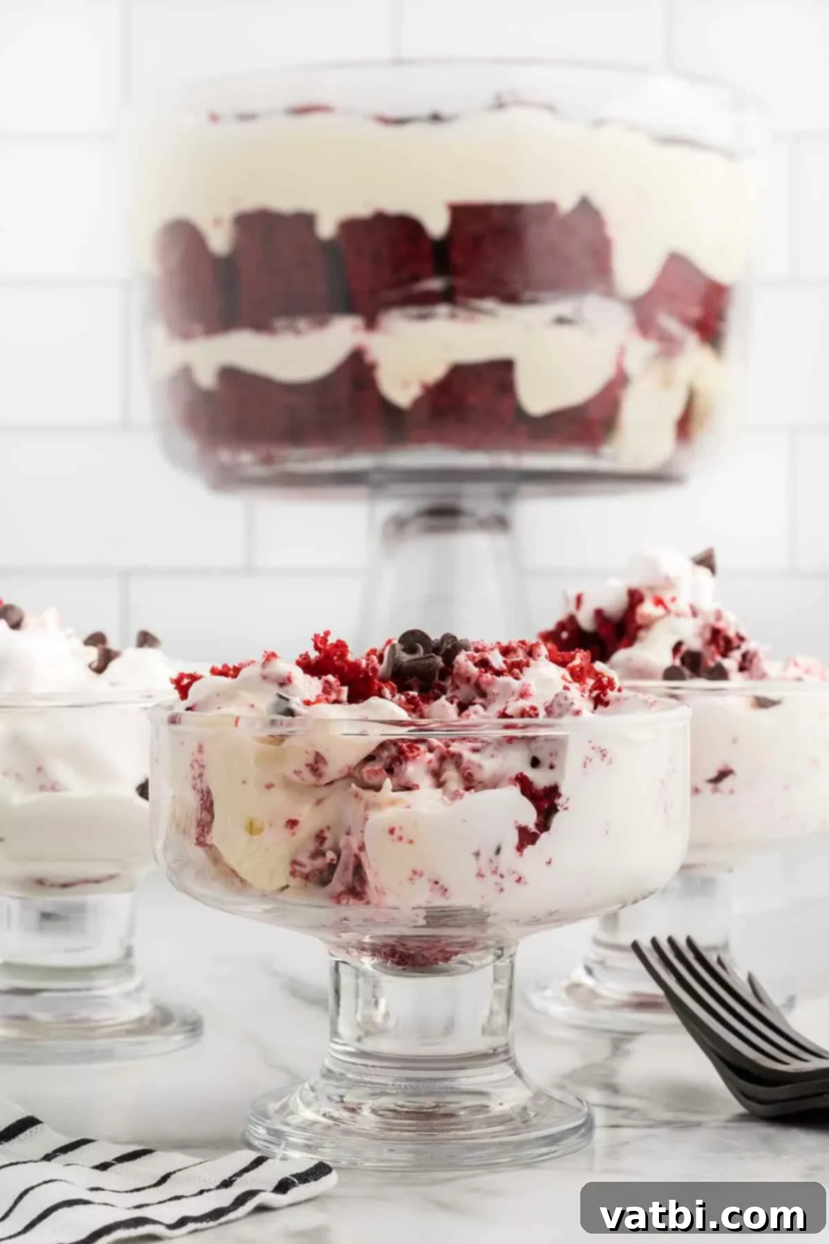 Crimson Velvet Trifle 2 Vibrant red velvet trifle layered beautifully in a clear serving bowl, topped with cream and chocolate chips.