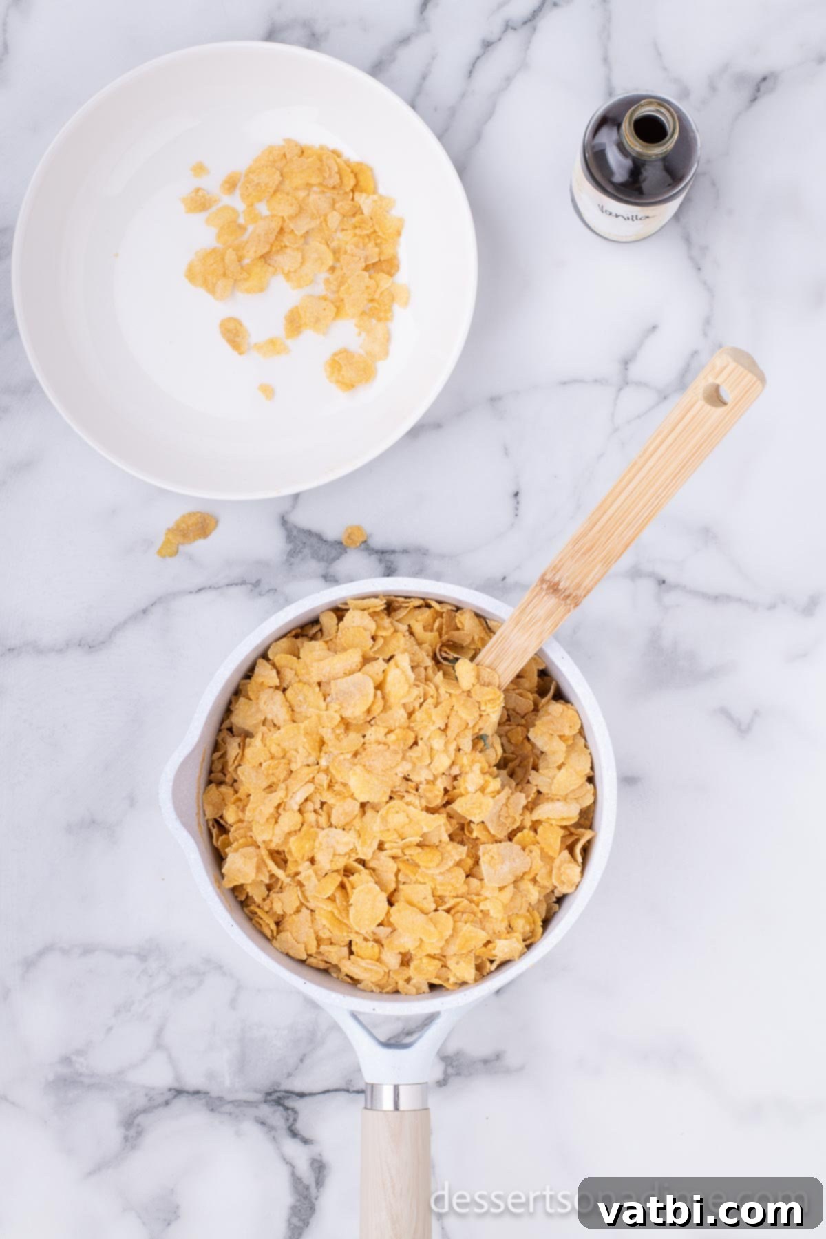Cornflake cereal being gently folded into the warm peanut butter mixture in a large saucepan.