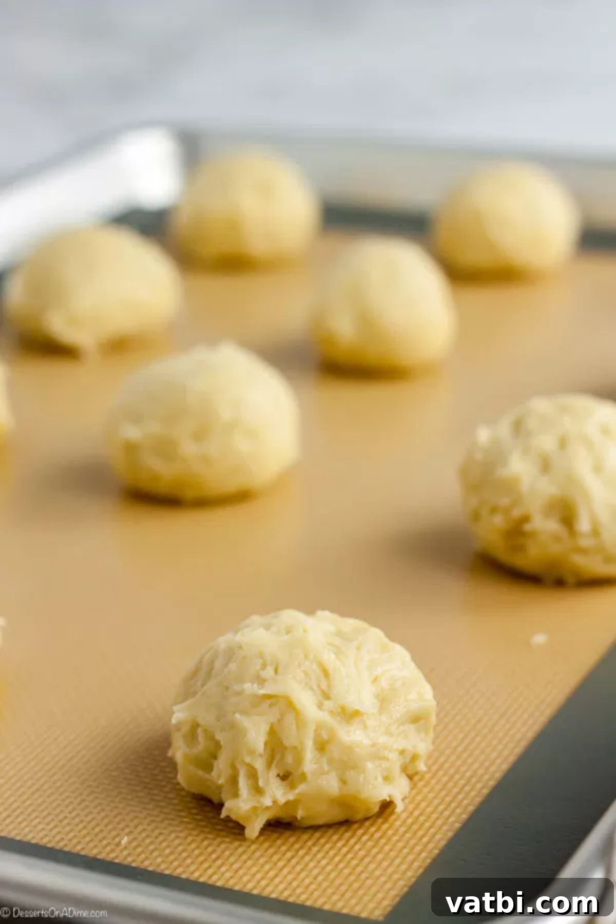Delicious Cream Cheese Cookies 5 Cream cheese cookie dough formed into dough balls and placed on a baking sheet.