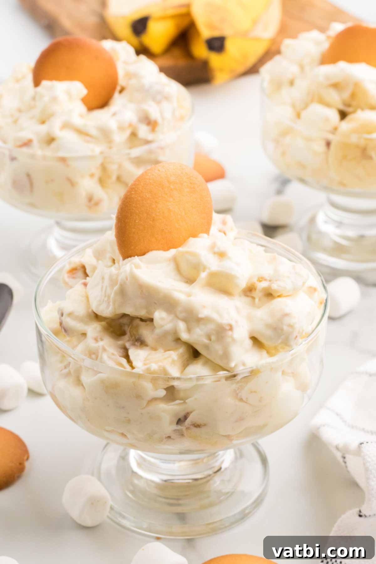 Whipped Banana Bliss 2 Individual serving dishes filled with creamy banana pudding fluff, garnished with vanilla wafer crumbs and banana slices.
