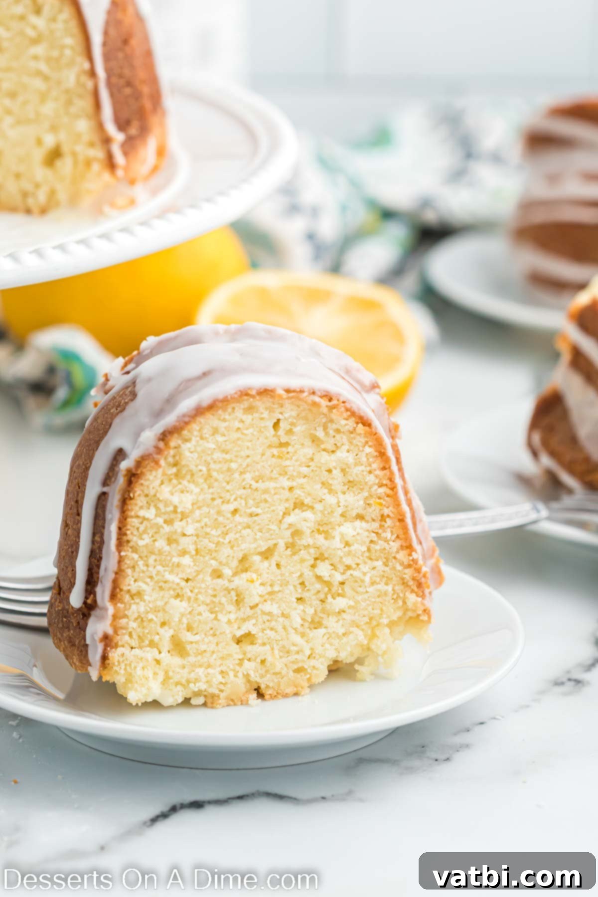 A beautifully sliced lemon pound cake, showing its moist crumb and a generous drizzle of lemon glaze.