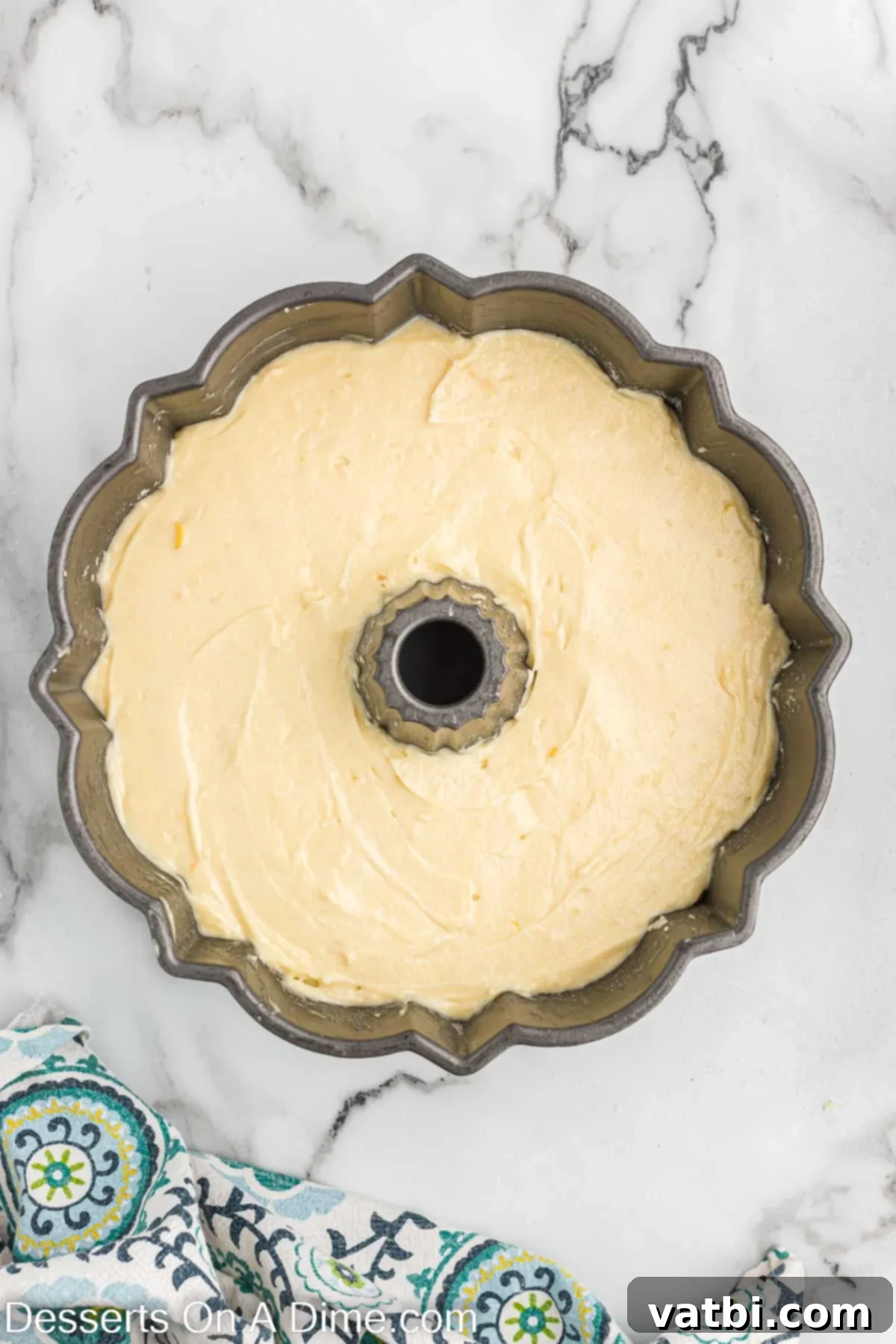 Smooth lemon pound cake batter being carefully poured into a greased and floured bundt pan.