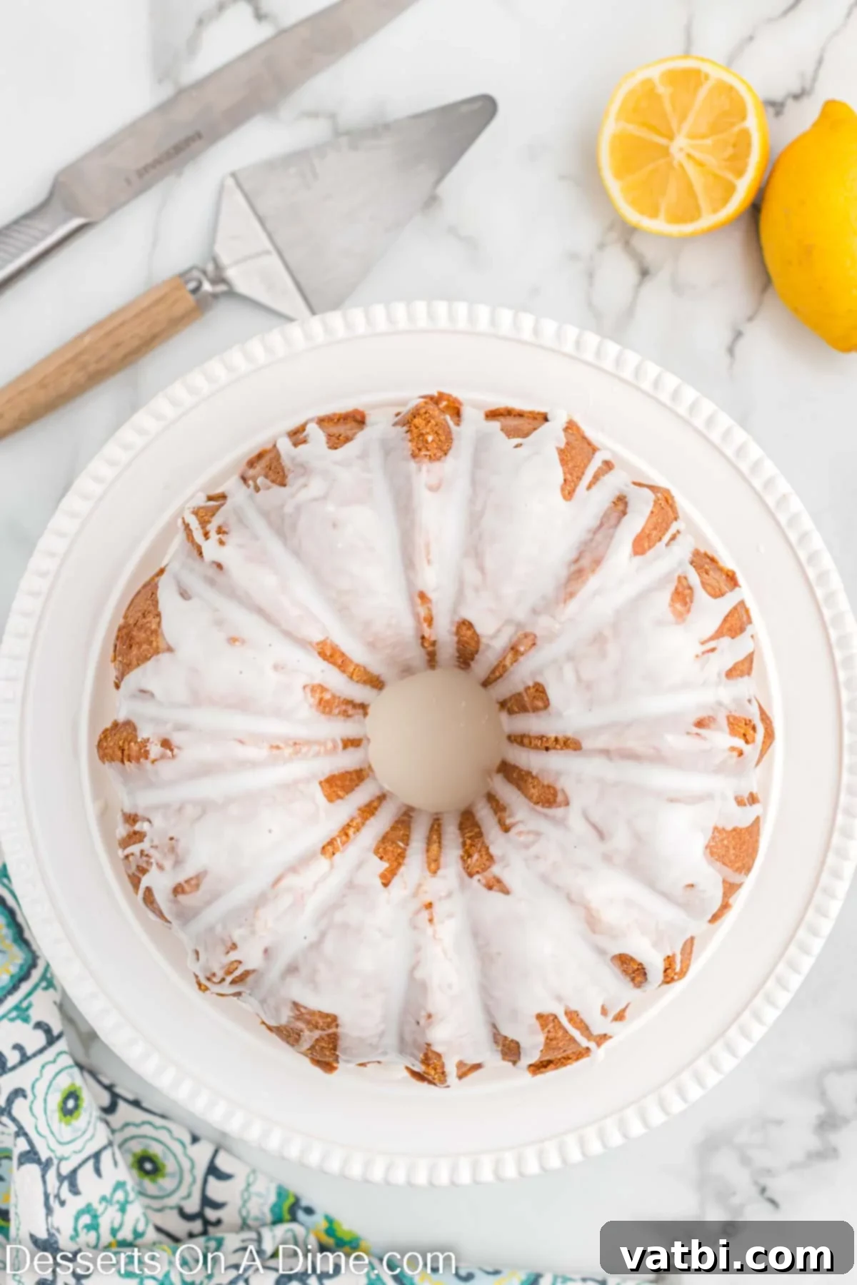 Thick lemon glaze being artfully drizzled over the completely cooled lemon pound cake.
