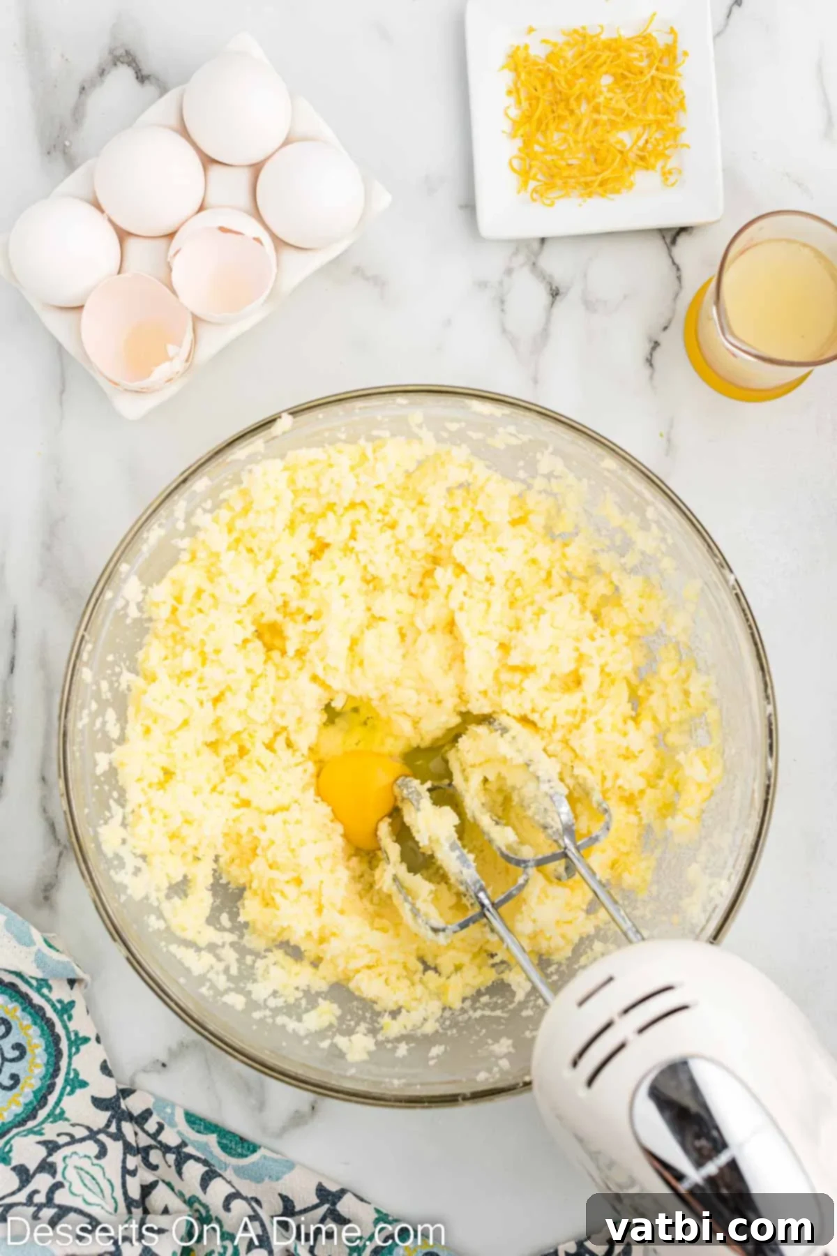Large eggs being added one at a time to the butter and sugar mixture.