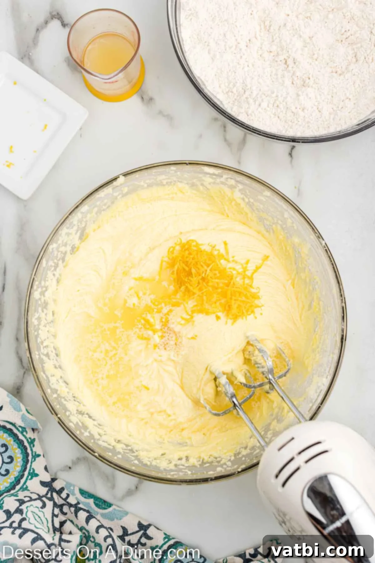 Fresh lemon zest being mixed into the creamy cake batter, infusing it with bright citrus aroma.