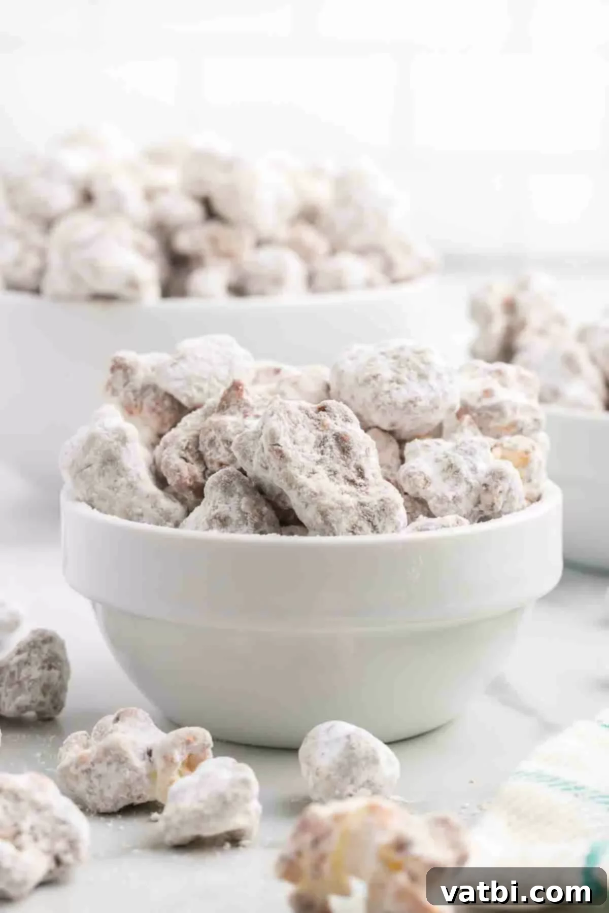 Muddy Buddies Popcorn 2 A large bowl filled with delicious Puppy Chow Popcorn, showcasing the powdered sugar coating and chocolate peanut butter drizzle.