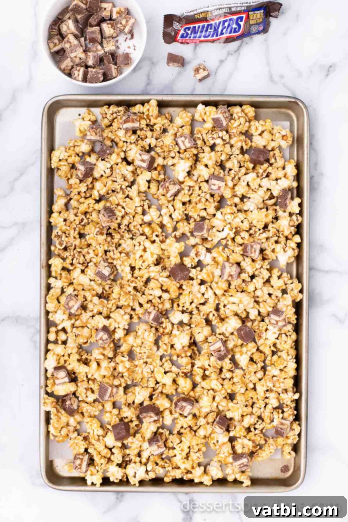 Snickers Popcorn Crunch 7 Chopped Snickers candy bars mixed into the baked caramel popcorn, with pieces softening.
