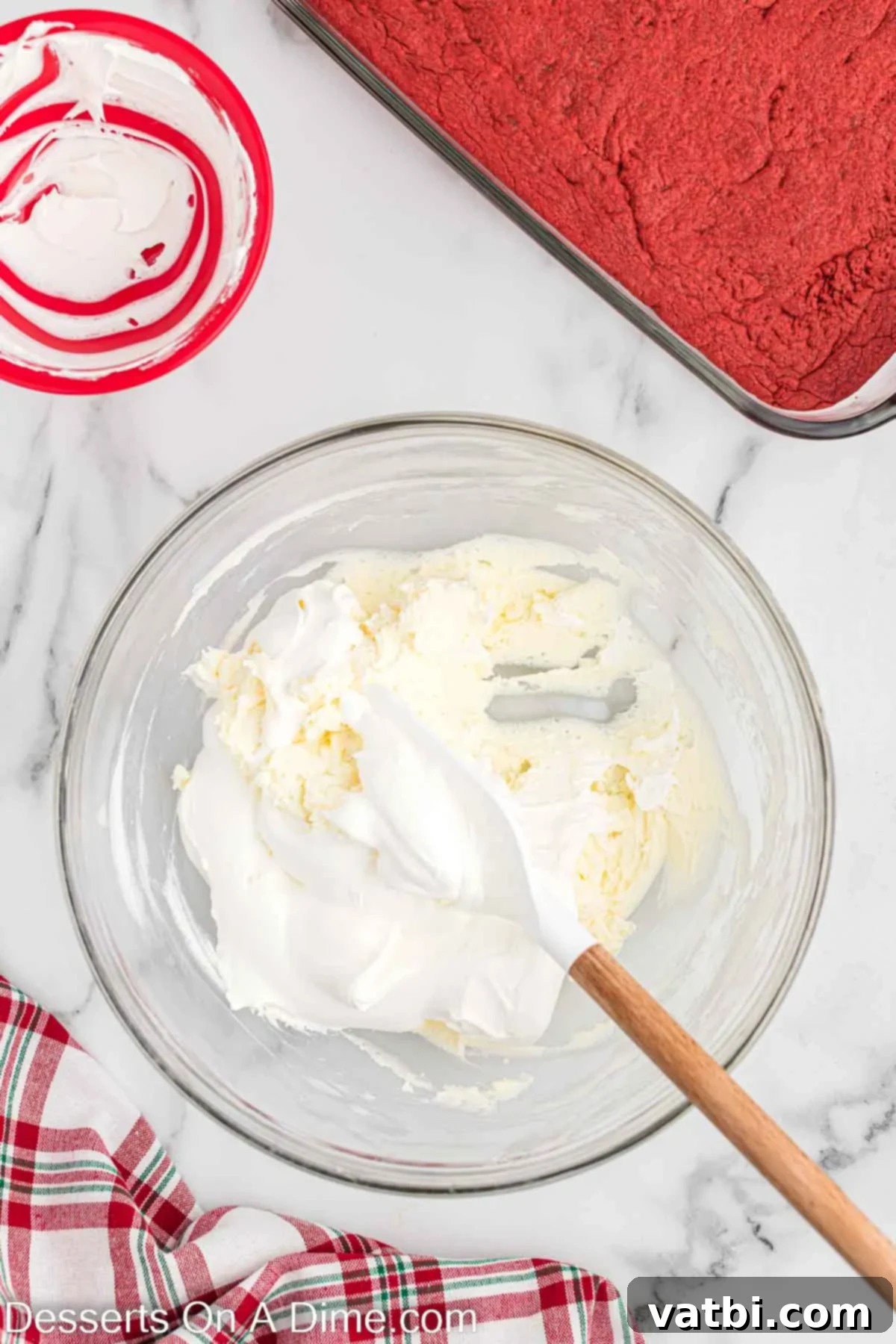 Christmas Layered Dream Dessert 5 Creamy peppermint cheesecake layer being mixed in a large bowl, showing its smooth, white consistency.