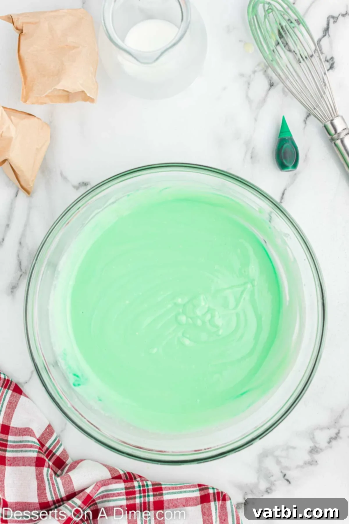Christmas Layered Dream Dessert 6 Instant white chocolate pudding mix being whisked with milk and green food coloring in a bowl, showing the vibrant green color.