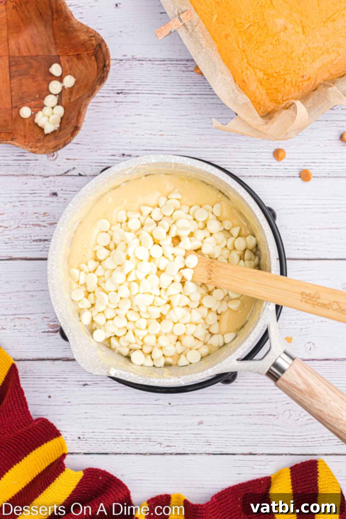 Magical Butterbeer Fudge 8 White chocolate chips being carefully added to the hot vanilla mixture in the saucepan, immediately after it's removed from heat.