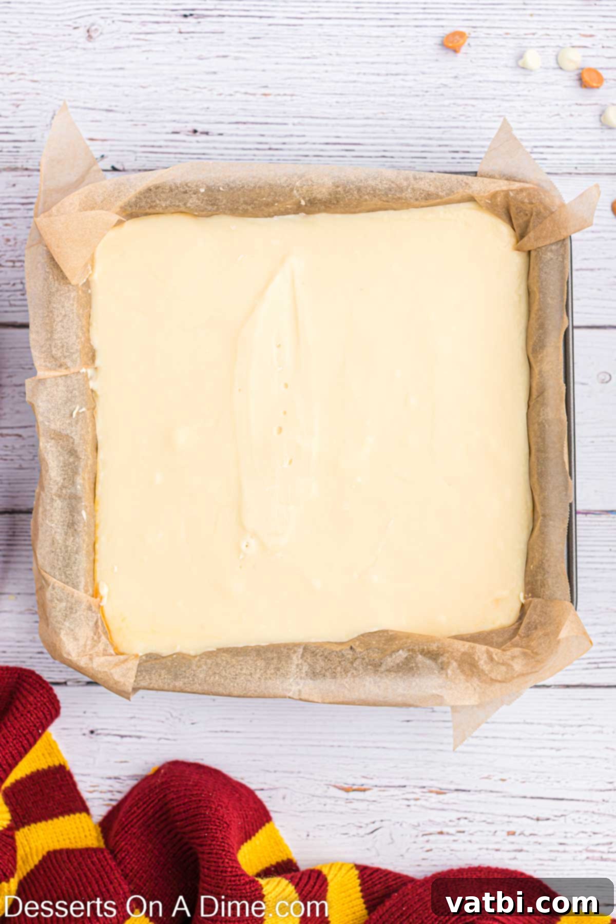 Magical Butterbeer Fudge 10 The white vanilla fudge layer is gently being poured and spread over the now-set butterscotch layer in the prepared baking dish, creating the iconic two-tone effect.
