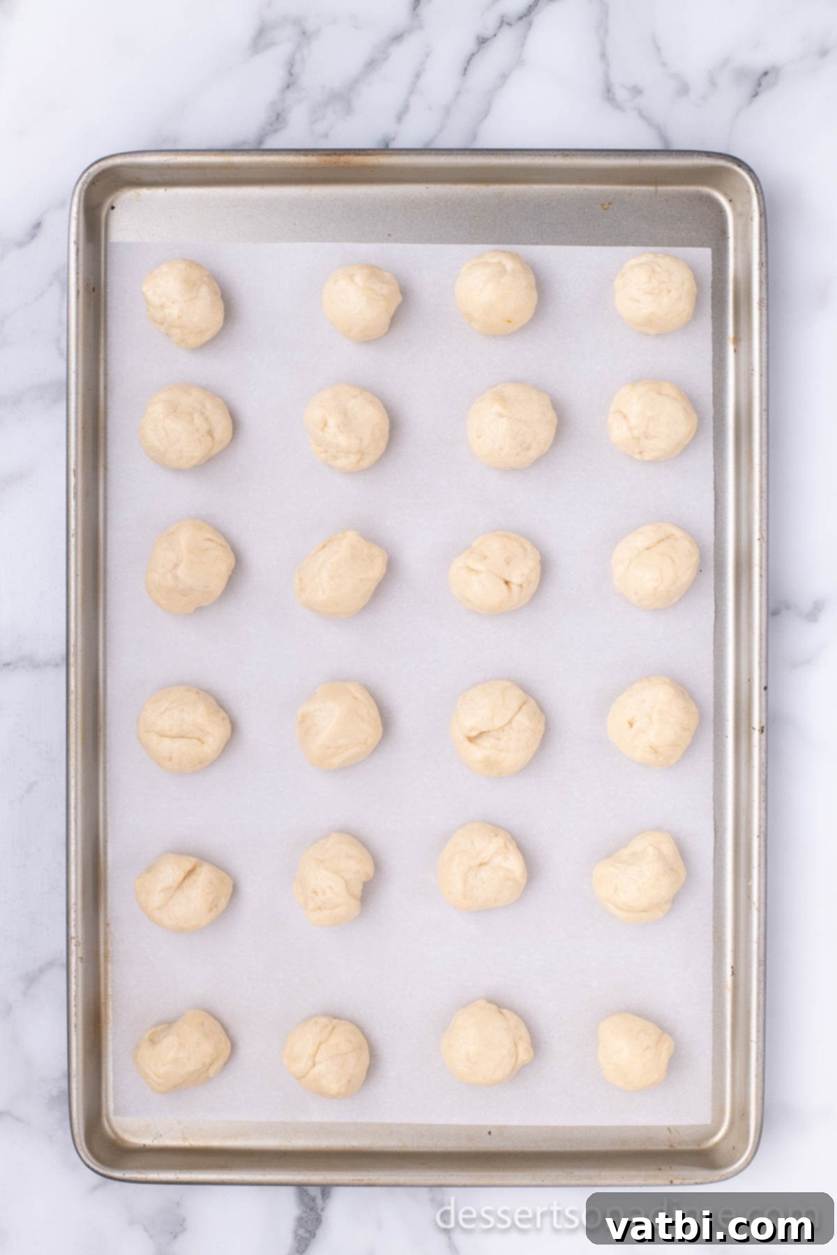 Pop the Sweetness: Krispy Kreme Donut Holes 15 Individual donut holes are arranged on a baking sheet, ready for frying and glazing.