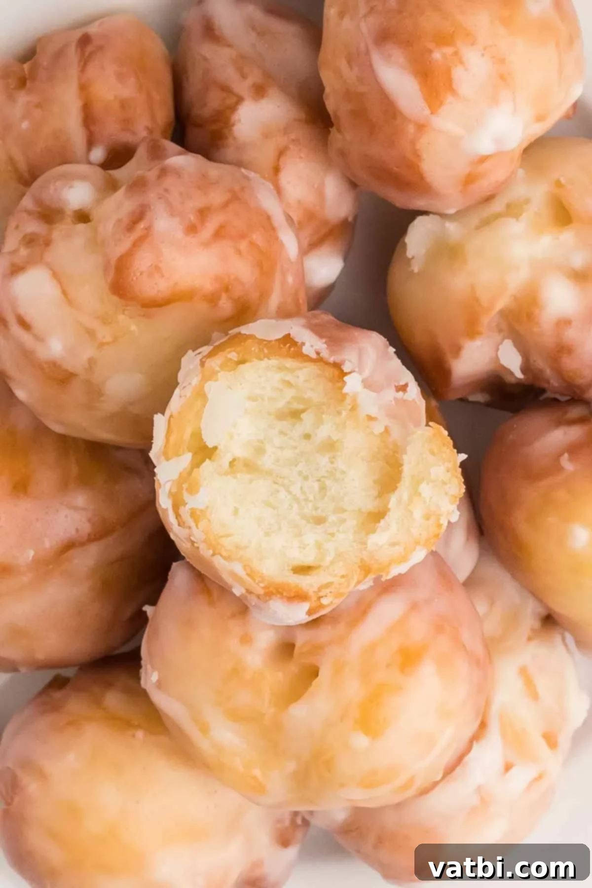 Pop the Sweetness: Krispy Kreme Donut Holes 20 A generous grouping of finished Krispy Kreme Donut Holes, each perfectly glazed and ready to be eaten.
