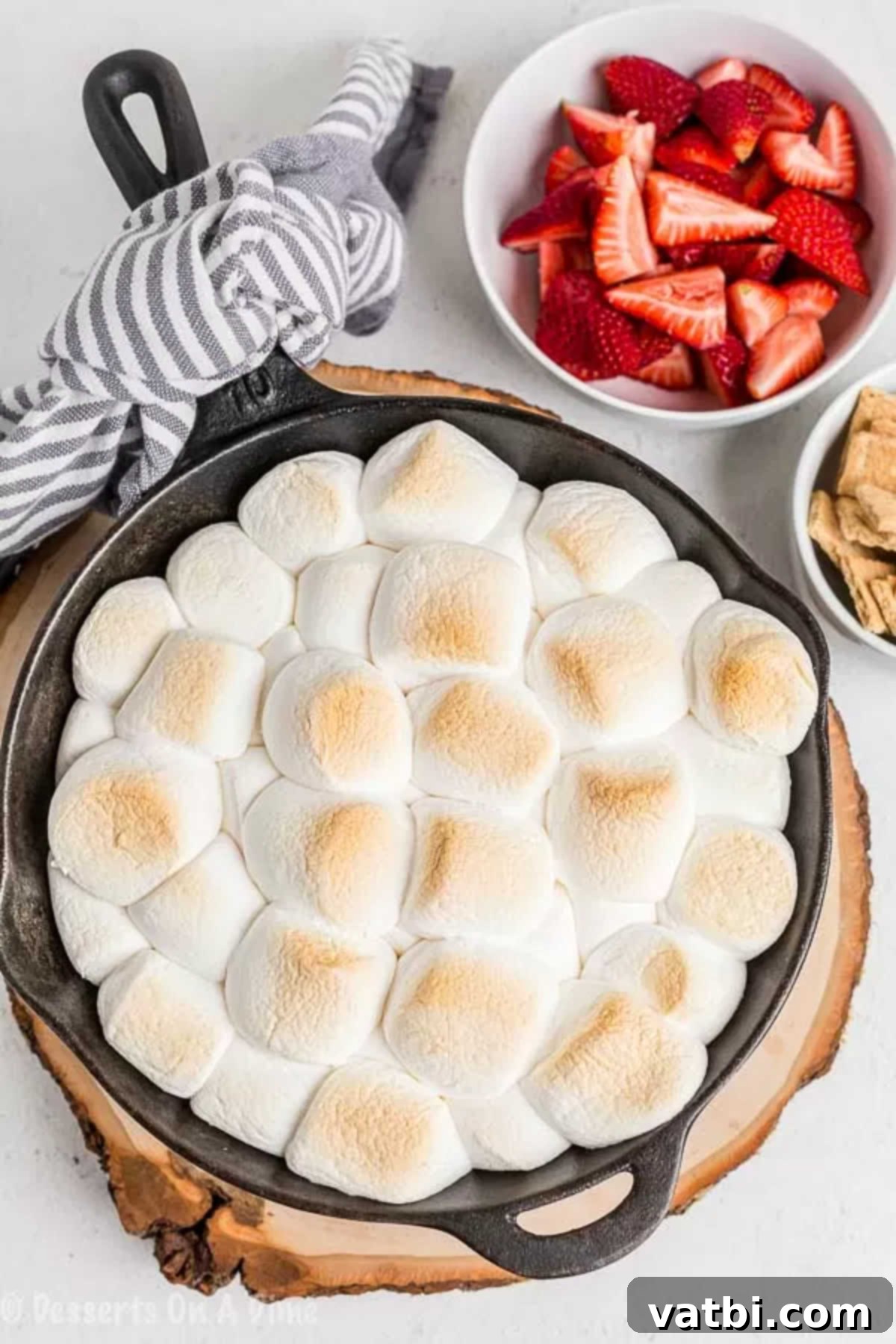Gooey Smores Dip 4 Marshmallows baked until golden brown on top of melted chocolate in a skillet.