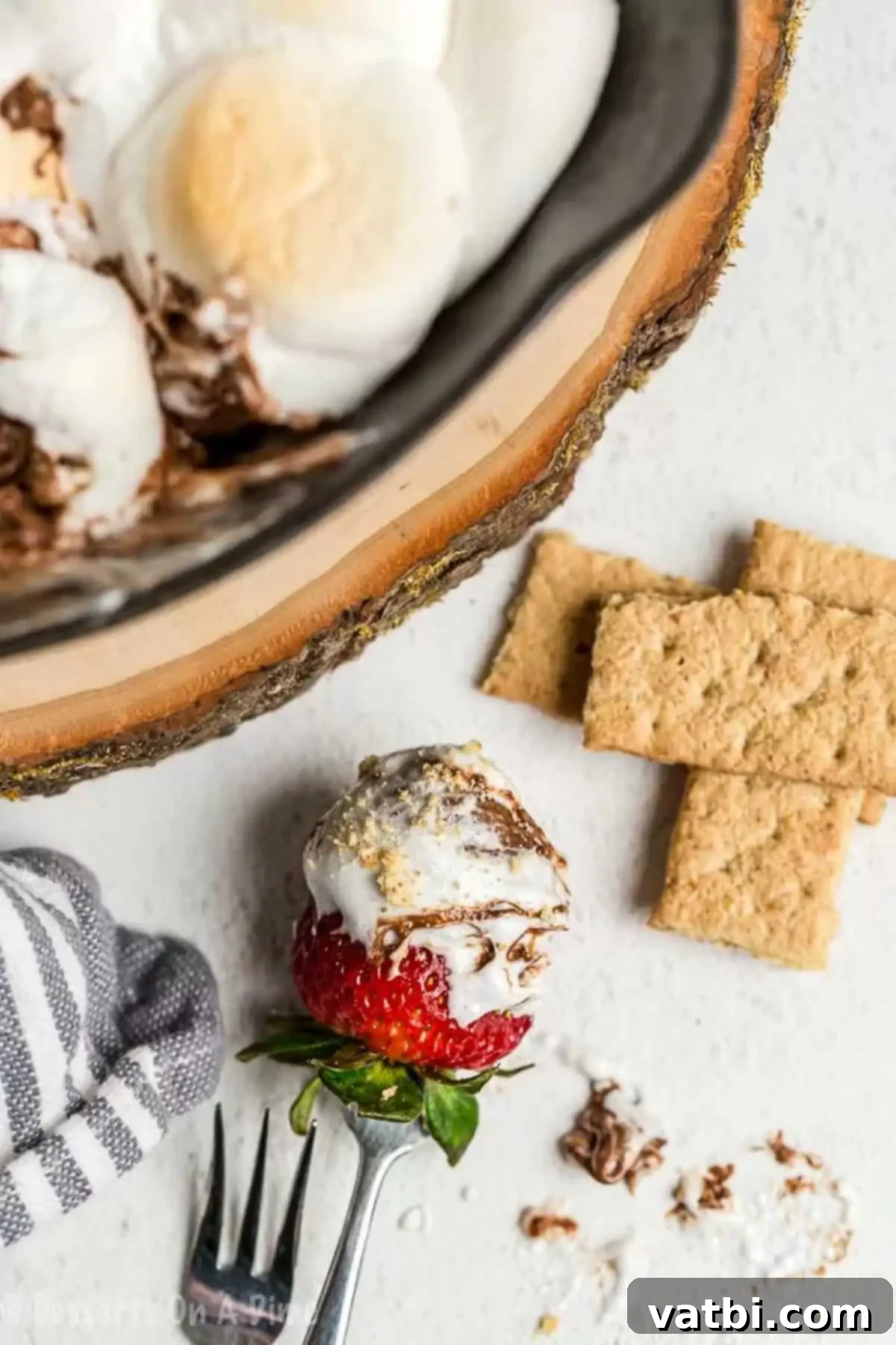 With only 2 ingredients needed, S'mores dip is the perfect treat to enjoy any day of the week. We love to make this dip for parties, snacks or just because. A strawberry dipped in s'mores dip, showcasing the delicious blend of melted chocolate and toasted marshmallow.